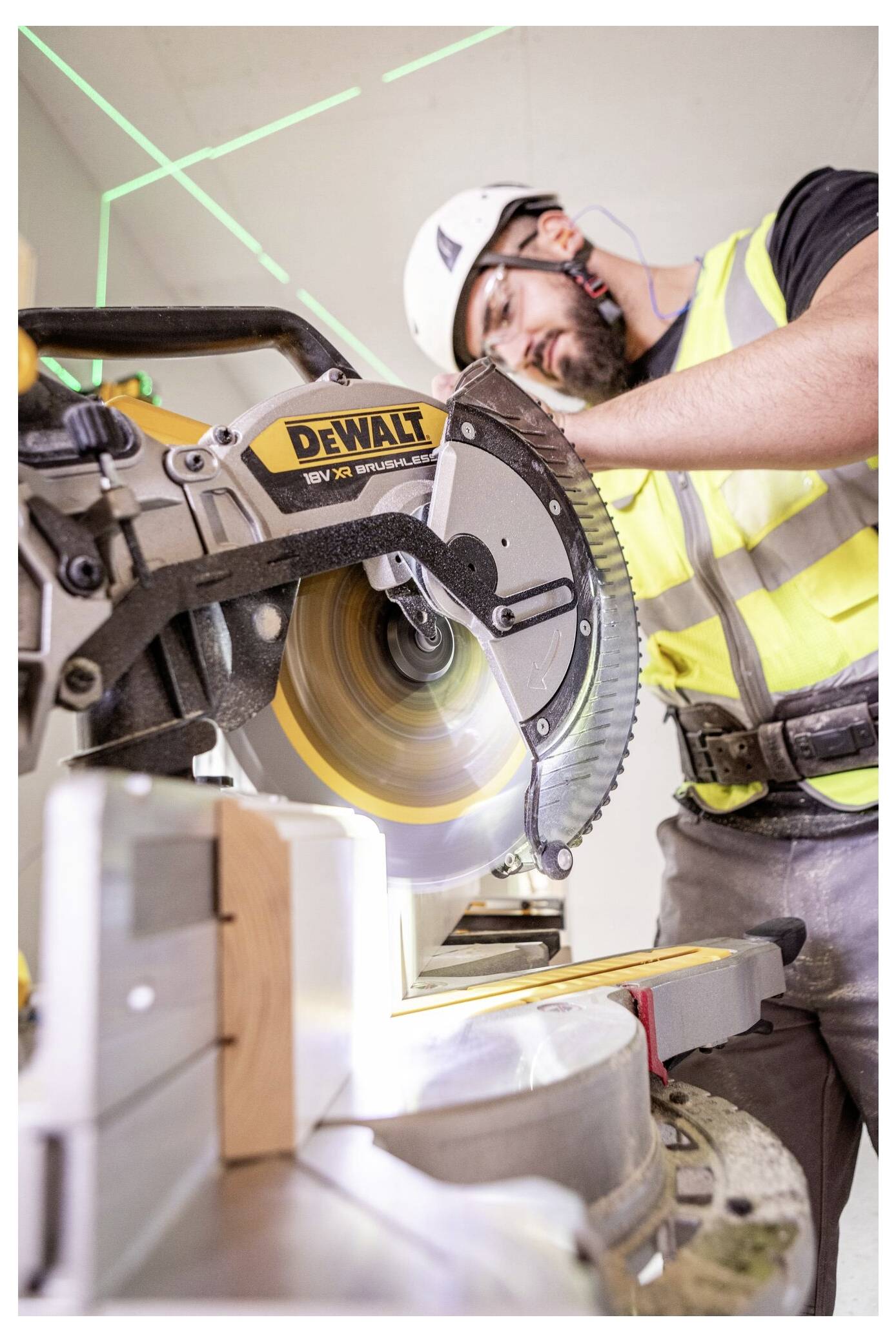 Eine Person mit Handschuhen kniet auf einer Baustelle und schneidet mit einem Universalmesser eine schwarze Materialfolie auf dem Boden zu.
