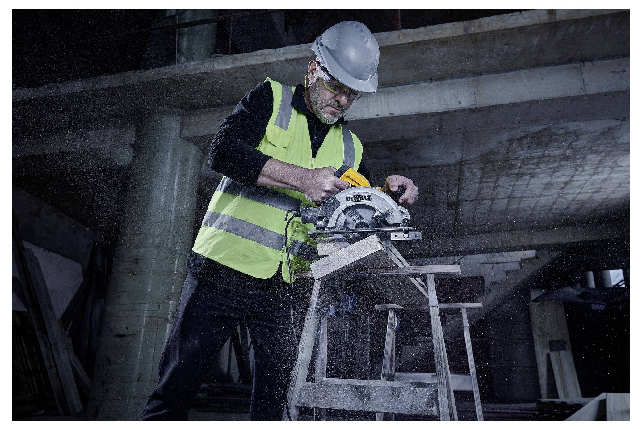 Ein Bauarbeiter in Schutzausrüstung benutzt eine Kreissäge, um ein Holzbrett auf einer Baustelle zu schneiden, wobei Sicherheitsmaßnahmen hervorgehoben werden.