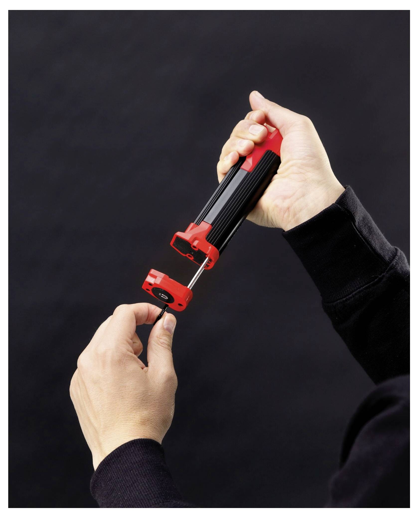 Eine Person mit Handschuhen schneidet Tapete mit einem Universalmesser neben einem Fenster und demonstriert damit eine Heimwerker- oder DIY-Aufgabe.