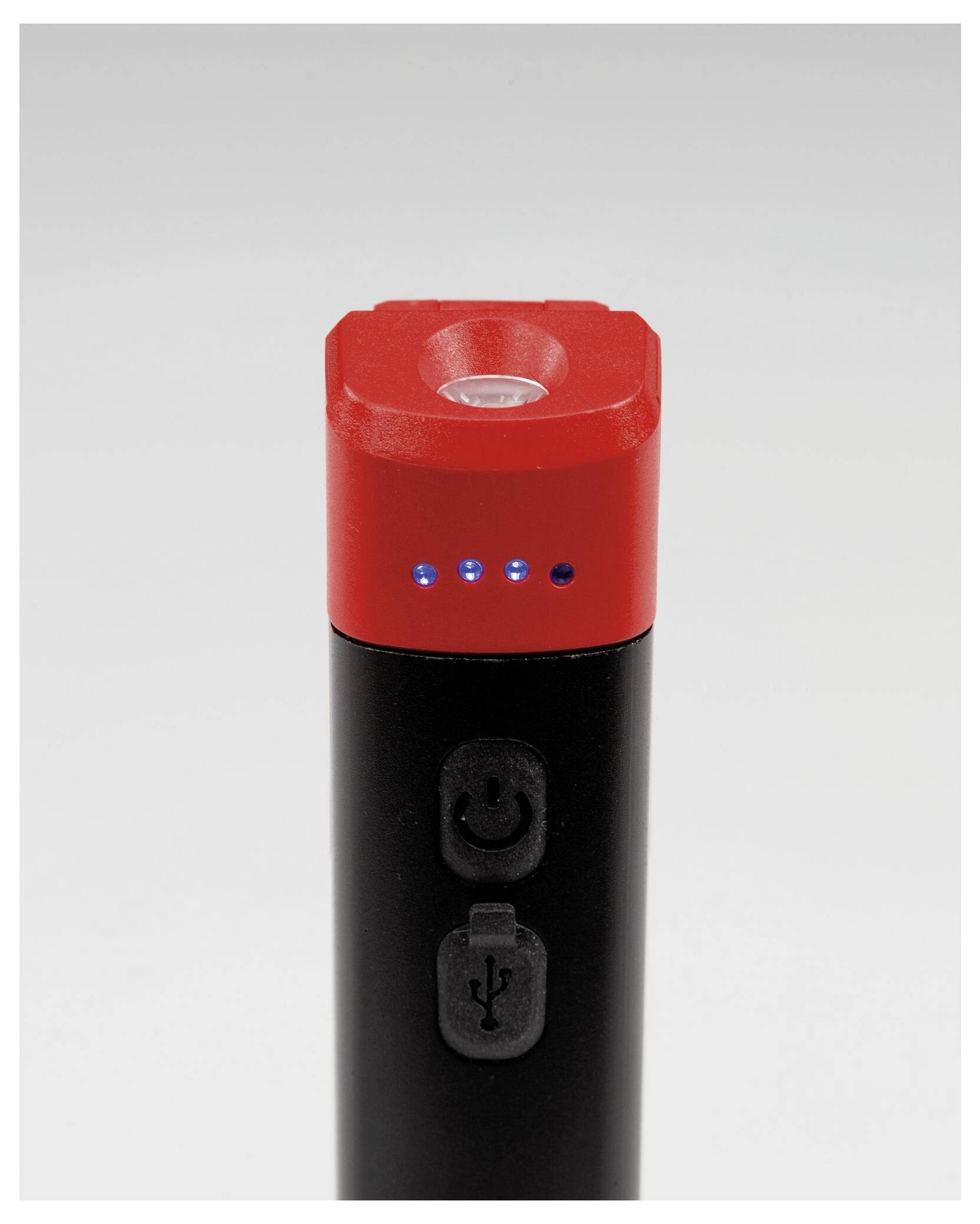 Ein schwarzes und rotes elektronisches Gerät mit LED-Anzeigen und Power- sowie USB-Knöpfen, vermutlich eine Powerbank oder ähnliches Gerät, auf neutralem Hintergrund.