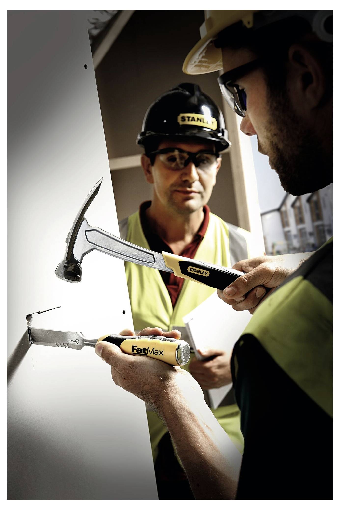 Ein Mann in einer Werkstatt organisiert verschiedene farbige Lagerkisten auf einem Tisch, mit Werkzeugen und Regalen im Hintergrund.