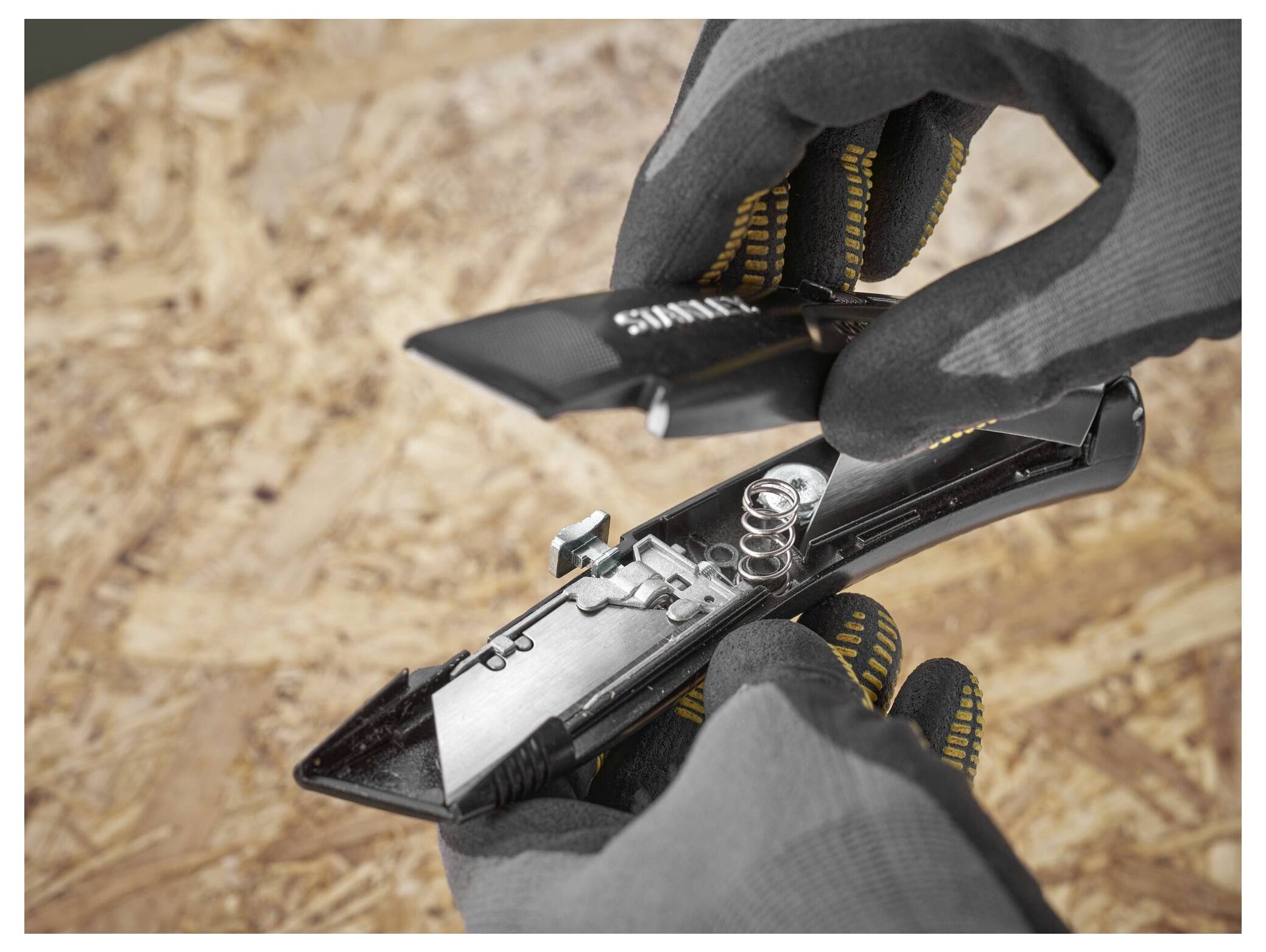 Eine Person geht über eine Holzrahmenbaubaustelle und trägt dabei eine Werkzeugkiste, Arbeitshandschuhe und Stiefel.