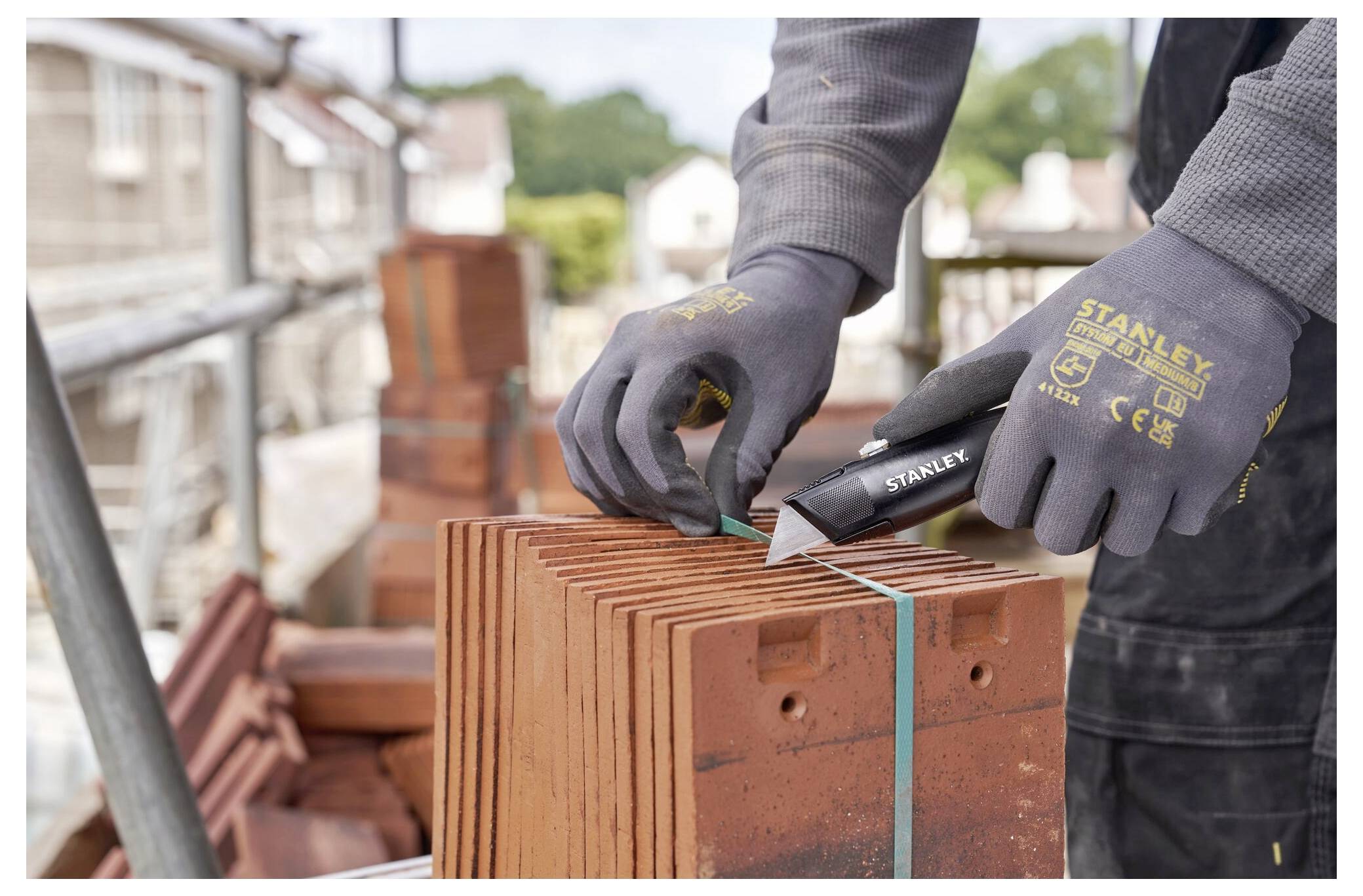 Eine Person in Schutzhandschuhen und einer Schutzbrille installiert Dämmmaterial an der Gebäudeaußenseite und schneidet es präzise um ein Fenster herum.
