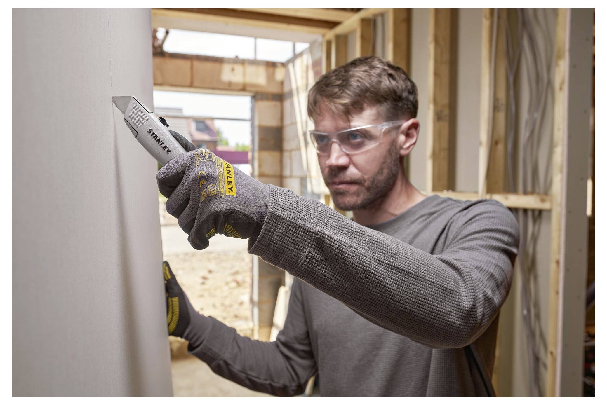 Eine Person, die eine Multitool-Zange verwendet, um Metalldraht auf einer silbernen reflektierenden Oberfläche zu biegen, trägt dabei schwarze Handschuhe für die Sicherheit.