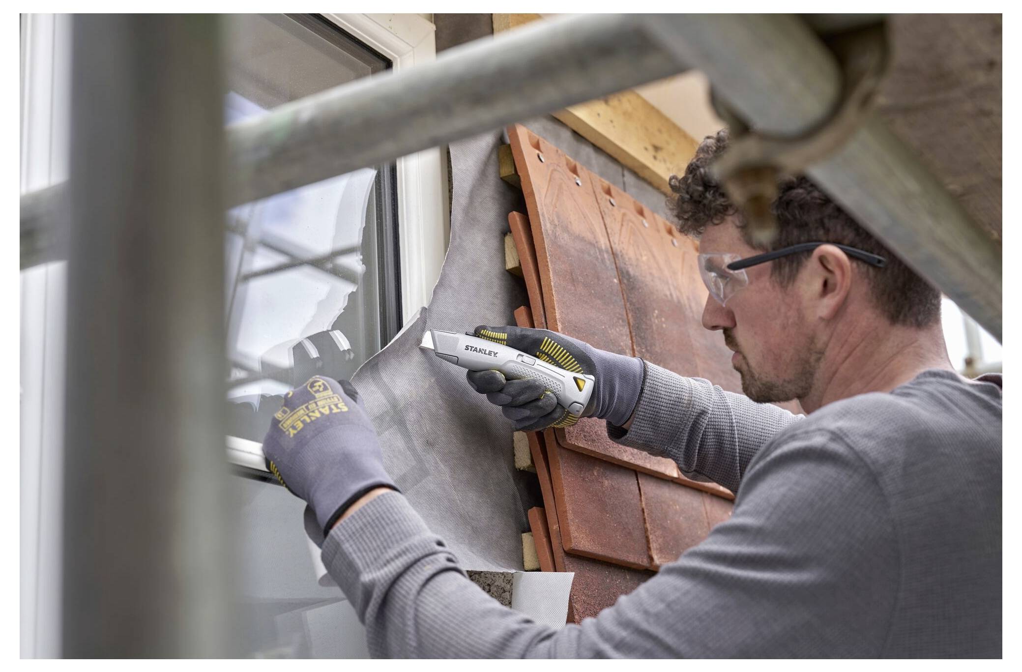 Ein Arbeiter in Schutzausrüstung bedient eine große elektrische Kreissäge auf einer Baustelle und sägt ein Stück Holz präzise zu.