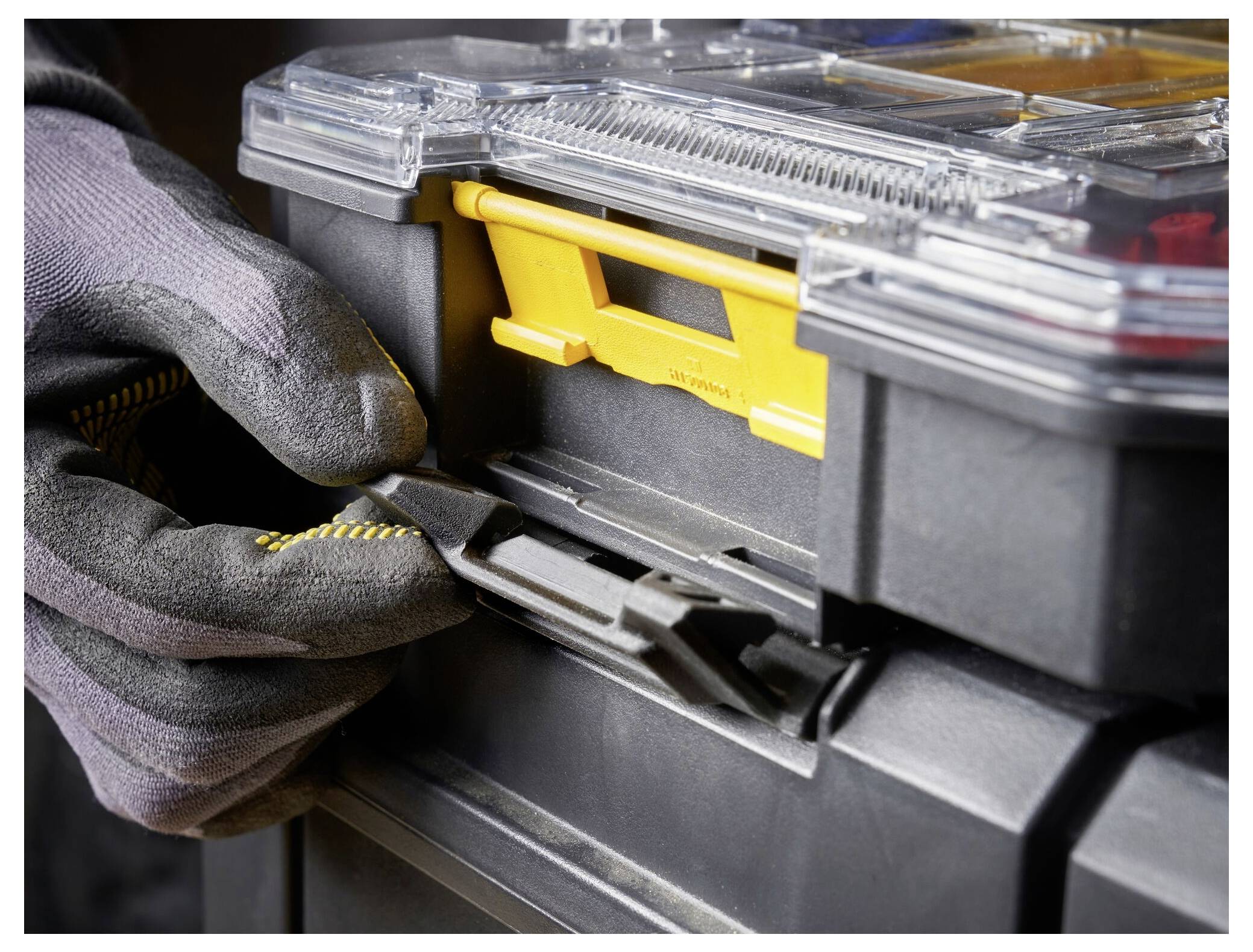 Eine Nahaufnahme einer Person, die Arbeitshandschuhe trägt und eine Werkzeugkiste verschlossen verriegelt, wobei ihre Langlebigkeit und der sichere Verschlussmechanismus hervorgehoben werden.