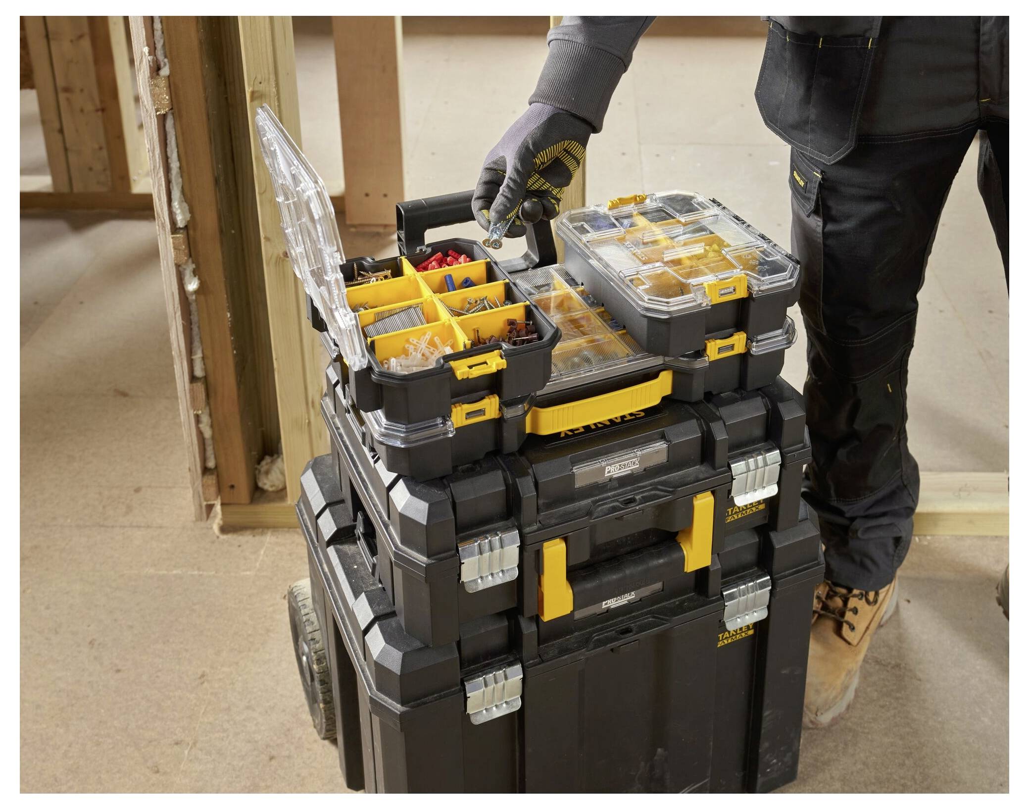 Eine Person in Schutzausrüstung benutzt eine Gehrungssäge, um Holz in geschlossenen Räumen zu schneiden. Die Säge trägt die Marke „DEWALT