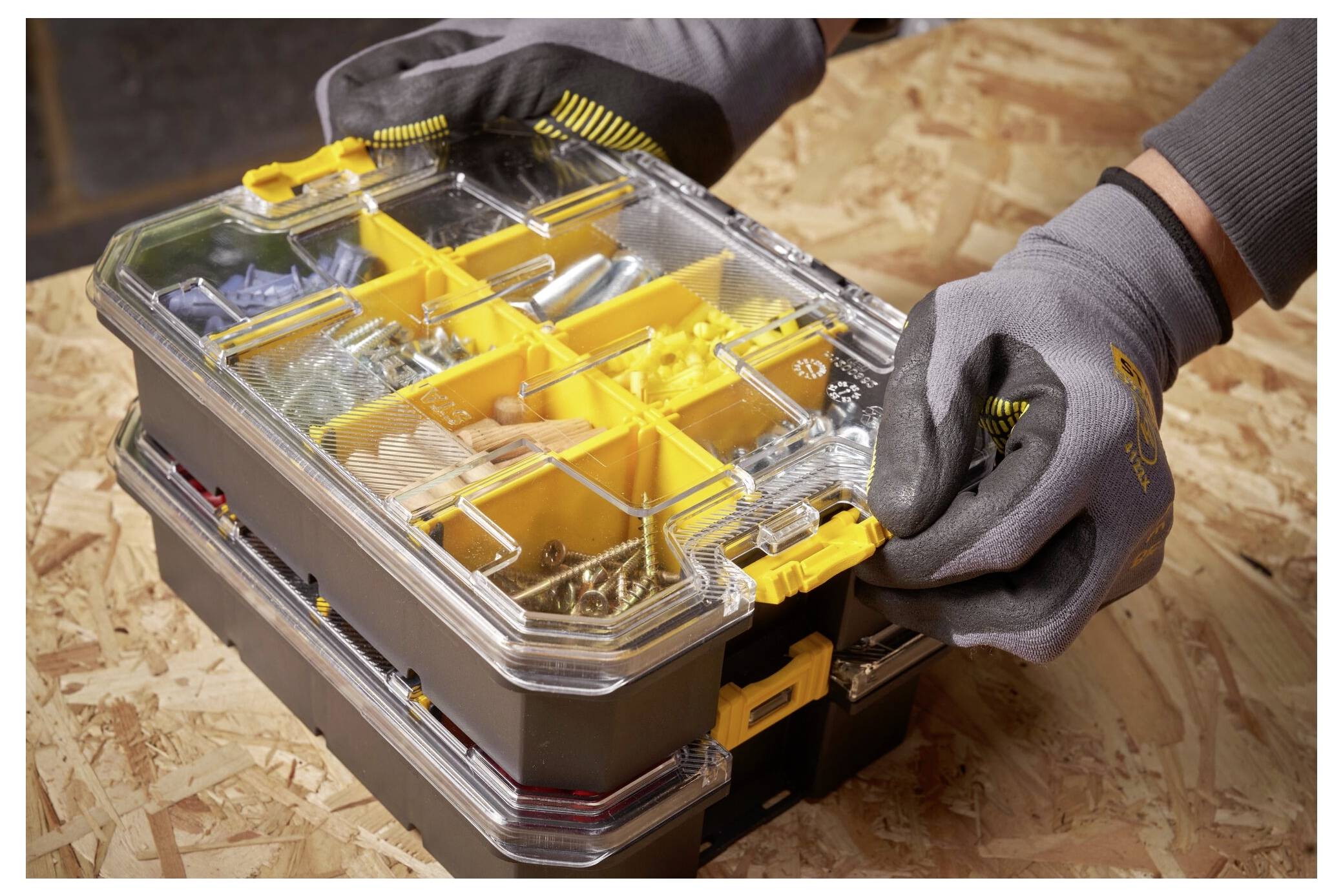 Eine Person setzt ein Akkupack in ein Elektrowerkzeug ein, wobei Sägespäne sichtbar sind, was auf Vorbereitung oder Wartung in einer Werkstattumgebung hindeutet.