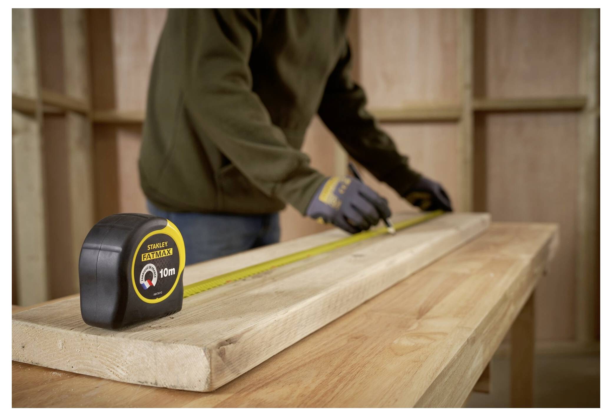 Eine Person verwendet einen roten und gelben Schraubendreher, um eine Schraube in einer Wandsteckdose zu installieren oder zu entfernen. Kunststofffolie bedeckt den Boden darunter.