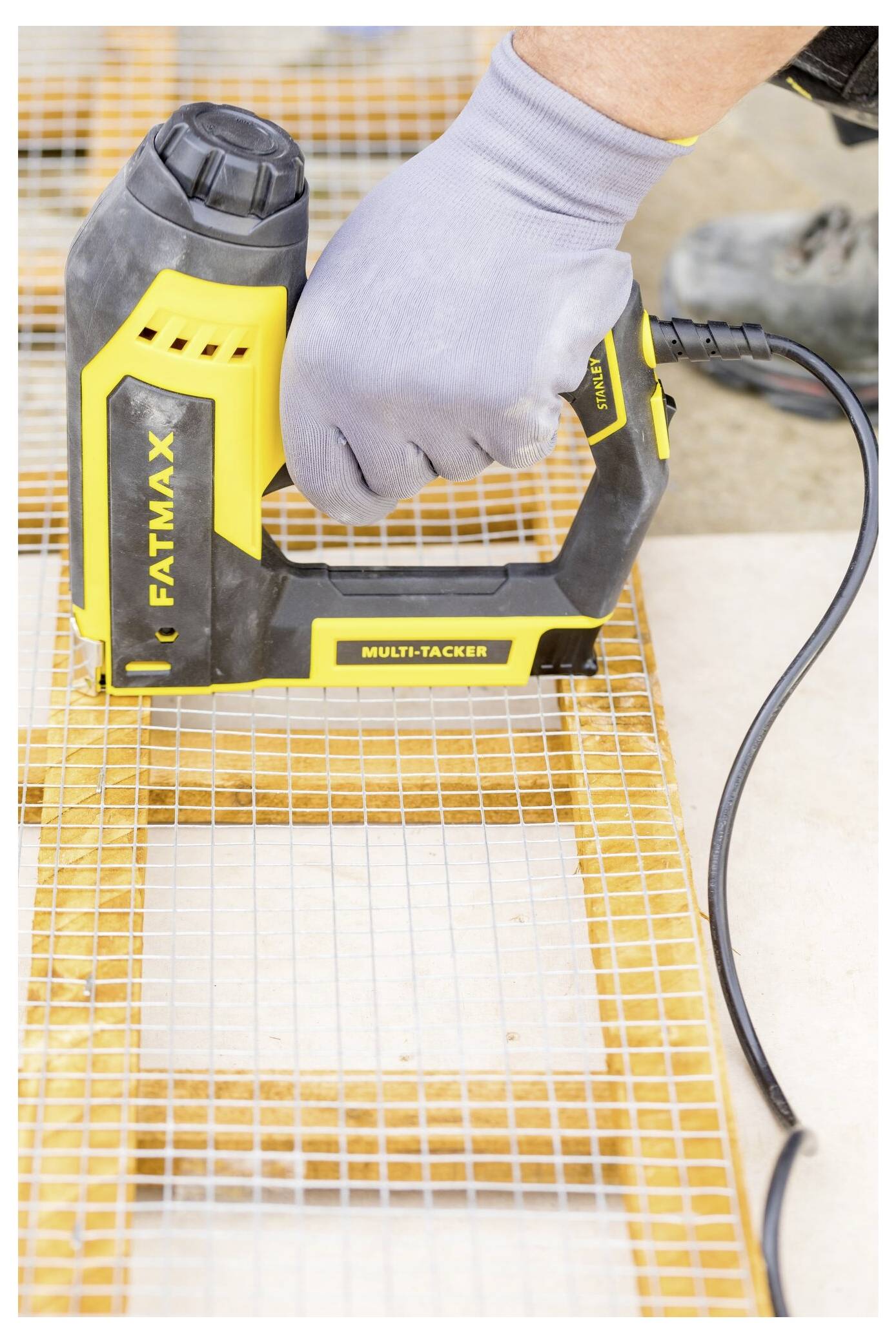 Eine Person trägt Handschuhe und benutzt einen gelb-schwarz gefärbten elektrischen Hefter mit der Bezeichnung 