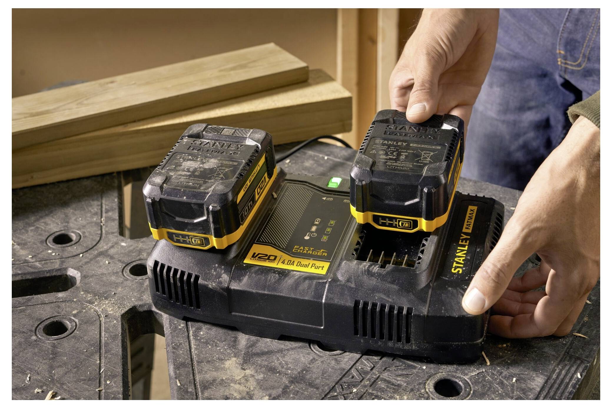 Hand, die ein USB-Kabel in ein Ladegerät für Elektrowerkzeug-Akkus einsteckt, mit einer Nahaufnahme des USB-Anschlusses und des Ladegeräts, das ein grünes Licht anzeigt.