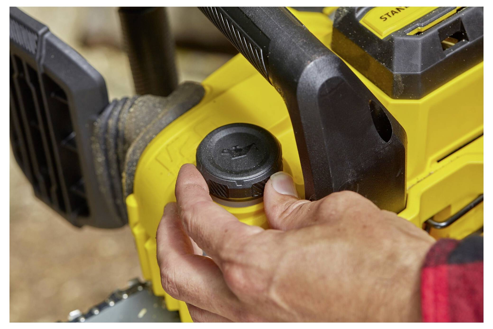 Eine Person, die zwei gelb-schwarze Akkus für Elektrowerkzeuge auf ein Stanley Fatmax Dual-Batterieladegerät auf einer Werkbank legt.