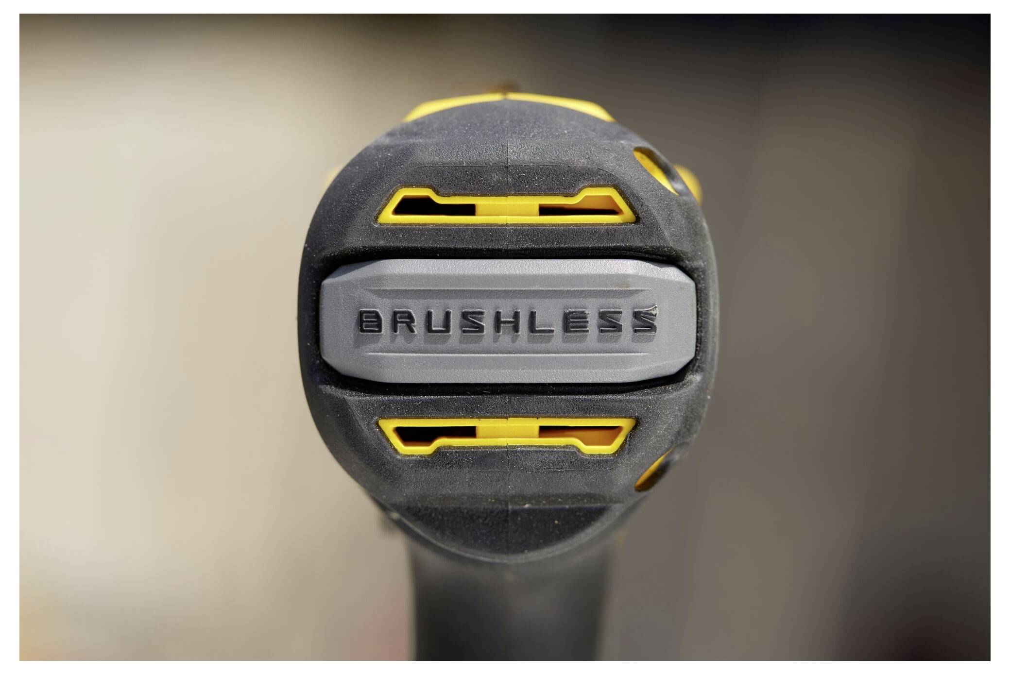 Ein Bauarbeiter nutzt ein gelbes Elektrowerkzeug in der Nähe von Holzständern auf einer Baustelle und deutet damit auf laufende Arbeiten hin.