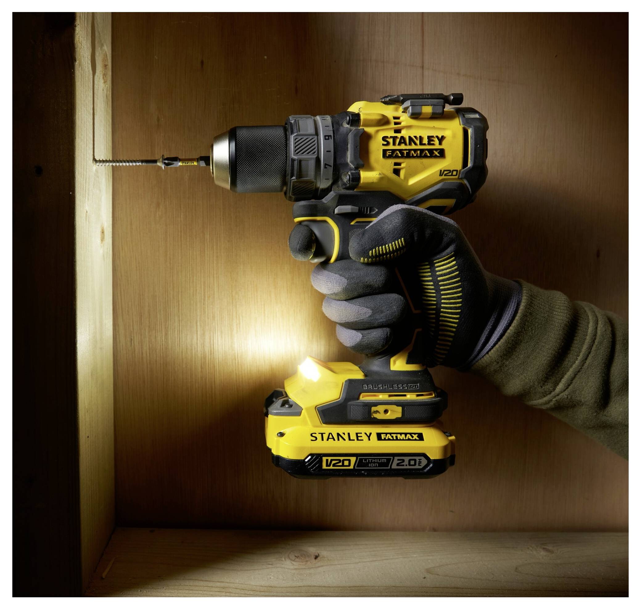 Zwei behandschuhte Hände halten ein gelbes kabelloses Laubgebläse mit einem abnehmbaren Akku, der gerade angebracht wird. Das Werkzeug ist mit der Marke „Stanley