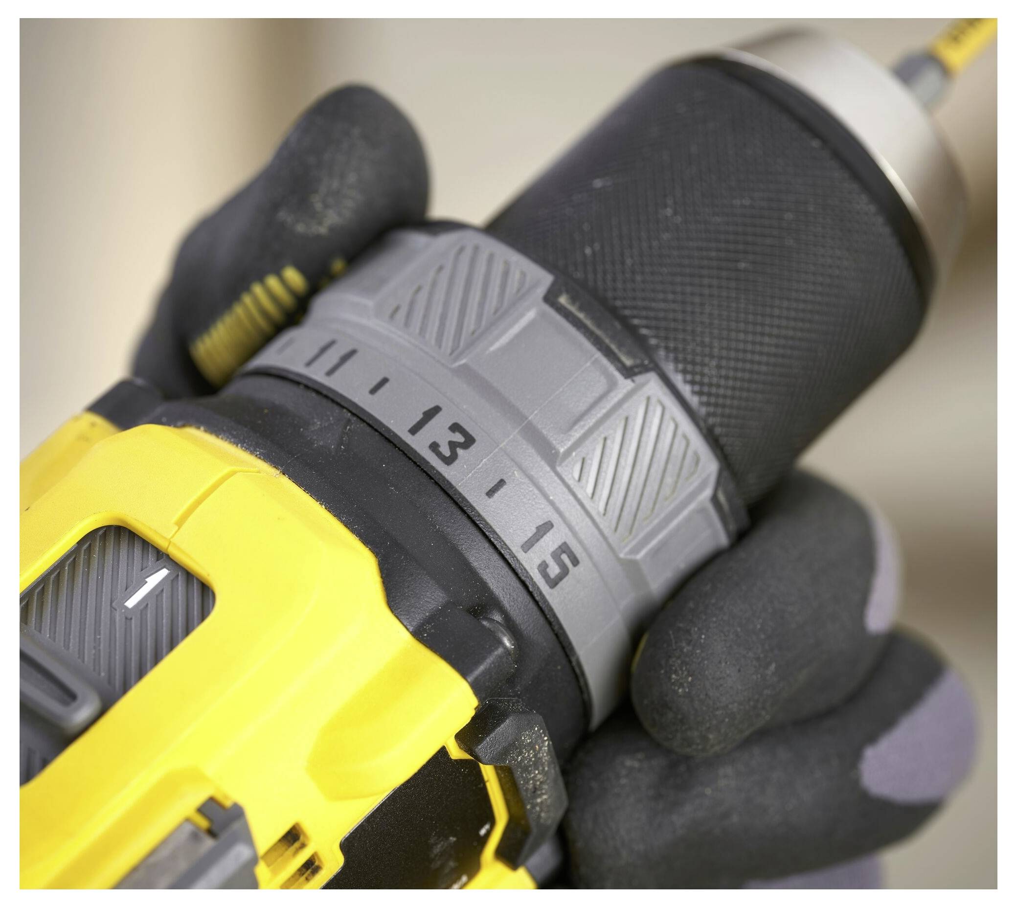 Eine Person in einem pelzgefütterten Wintermantel und Handschuhen stellt Einstellungen an einem gelben Schneefräser mit der Aufschrift „STANLEY