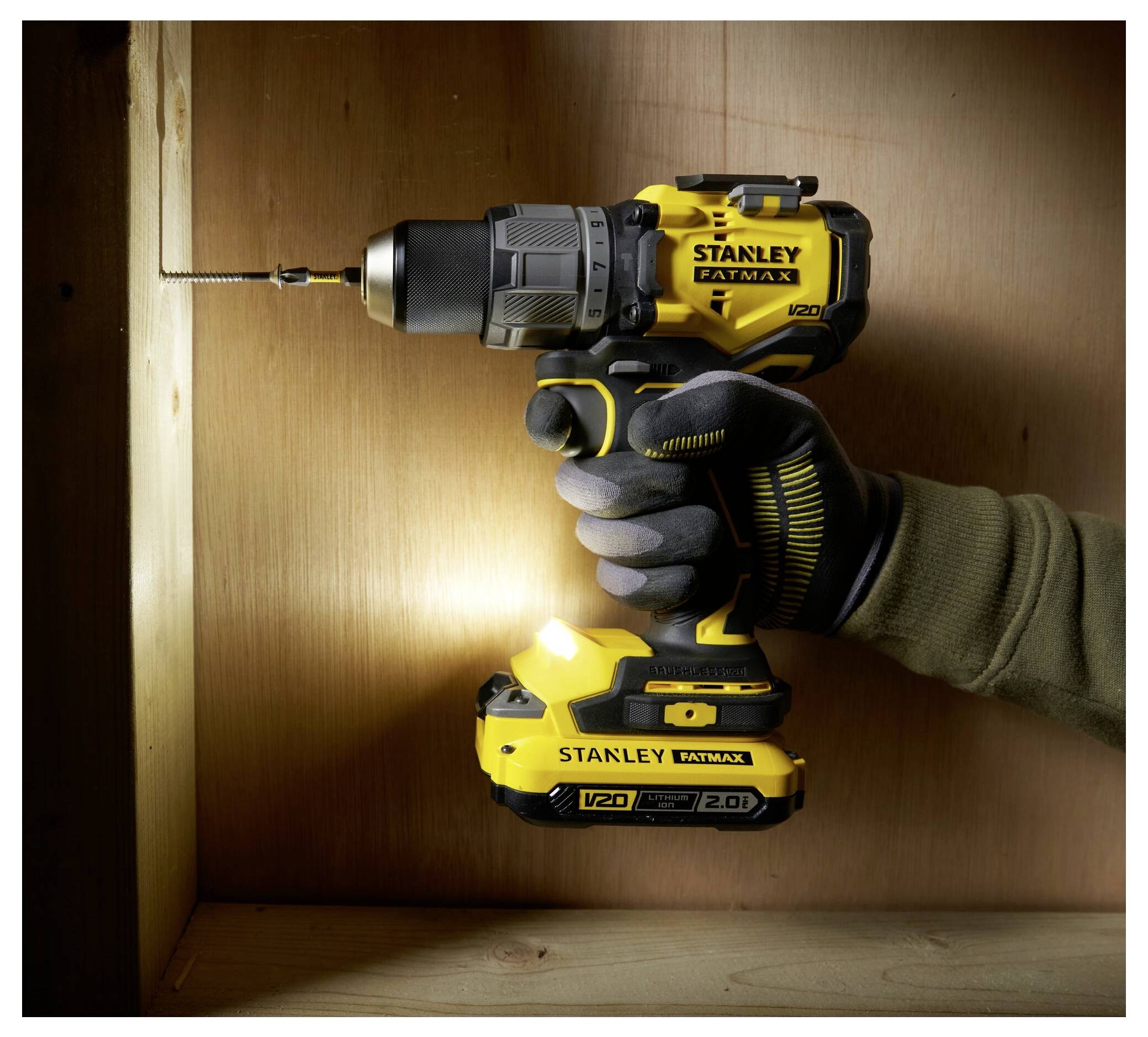 Eine Person benutzt einen gelben kabellosen Bohrer, um in eine Holzoberfläche zu schrauben, beleuchtet den Arbeitsbereich und zeigt die Fähigkeiten des Bohrers.