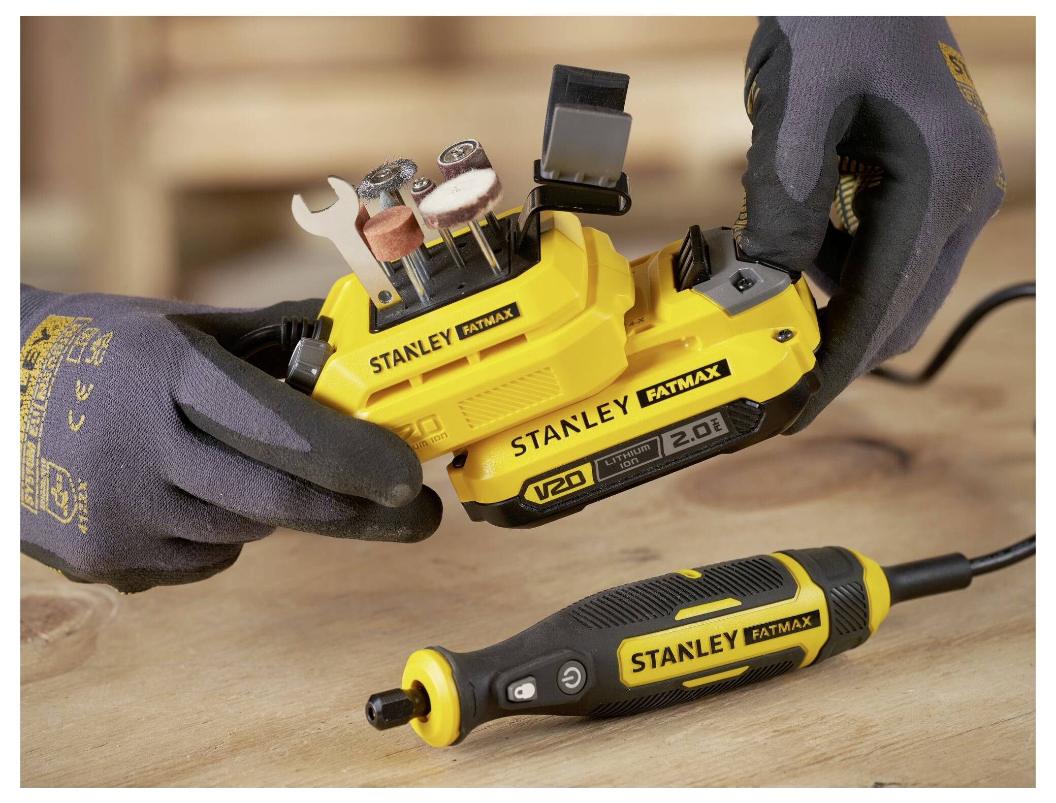 Ein gelber und schwarzer kabelloses Bohrgerät mit einer aufgewickelten Schnur sitzt auf einer passenden Ladestation. Der Markenname „STANLEY