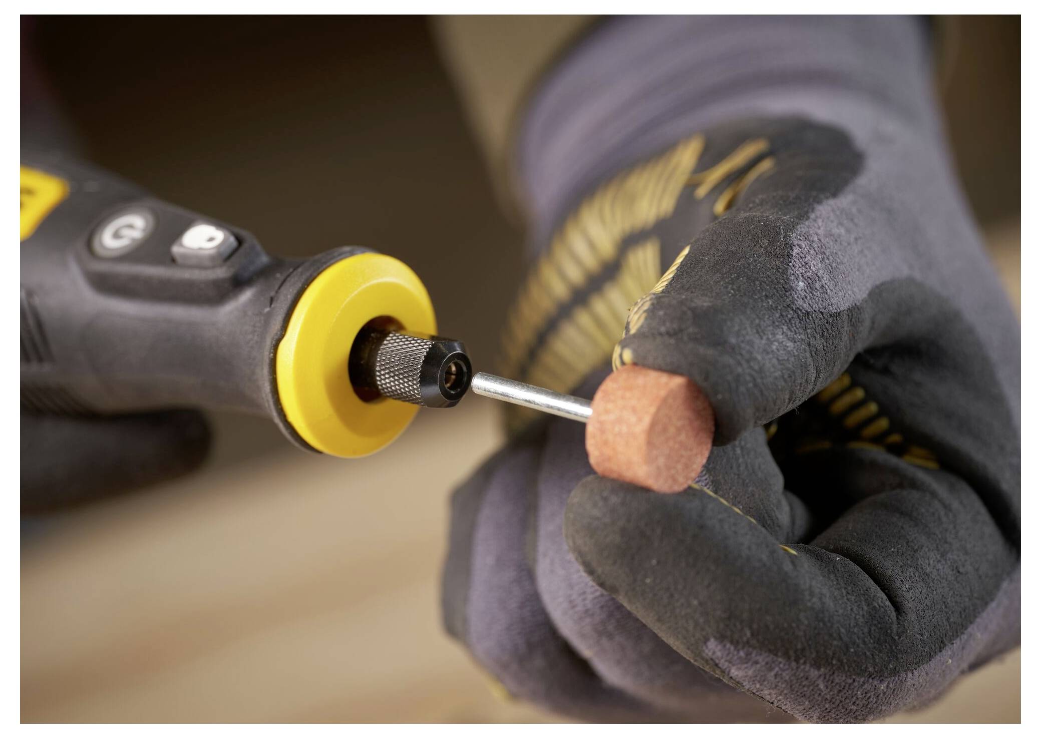 Eine Person benutzt einen gelb-schwarzen bürstenlosen Bohrer gegen eine Oberfläche und trägt dabei einen grauen Handschuh. Der Bohrer zeigt die Aufschrift „BRUSHLESS