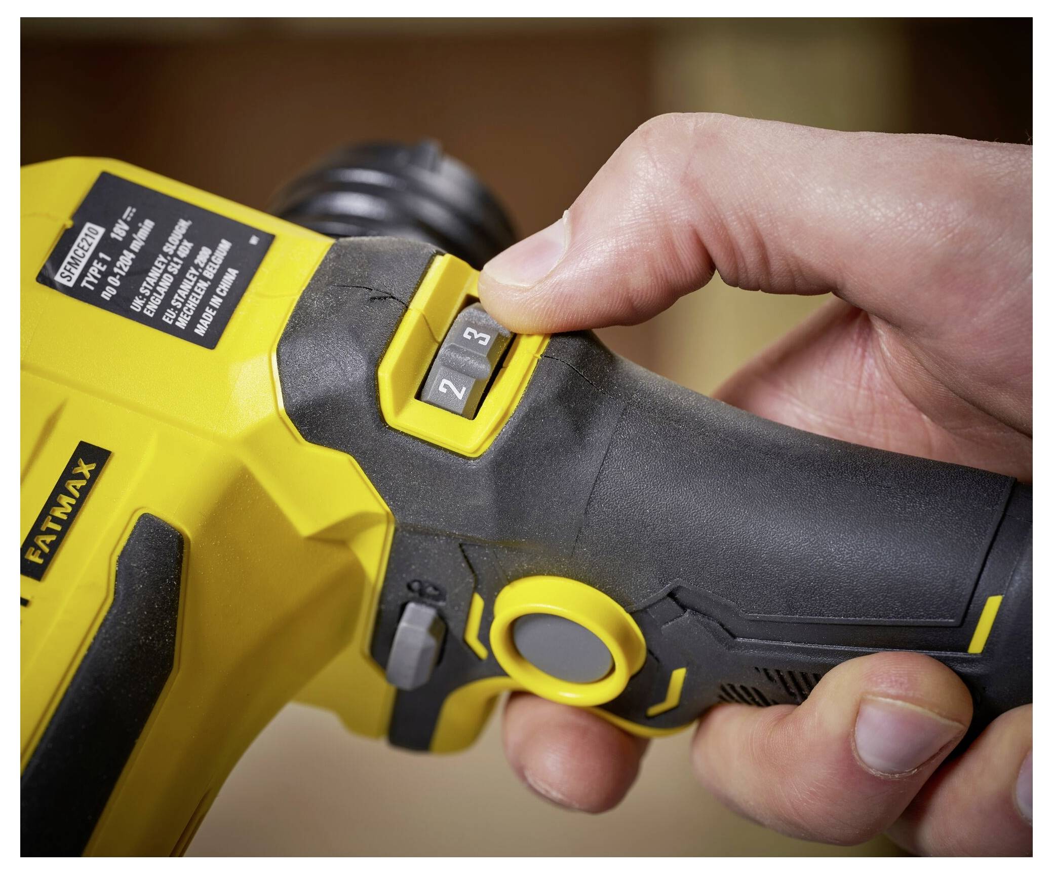 Hand stellt Geschwindigkeitseinstellung am gelben Griff eines Elektrowerkzeugs ein.