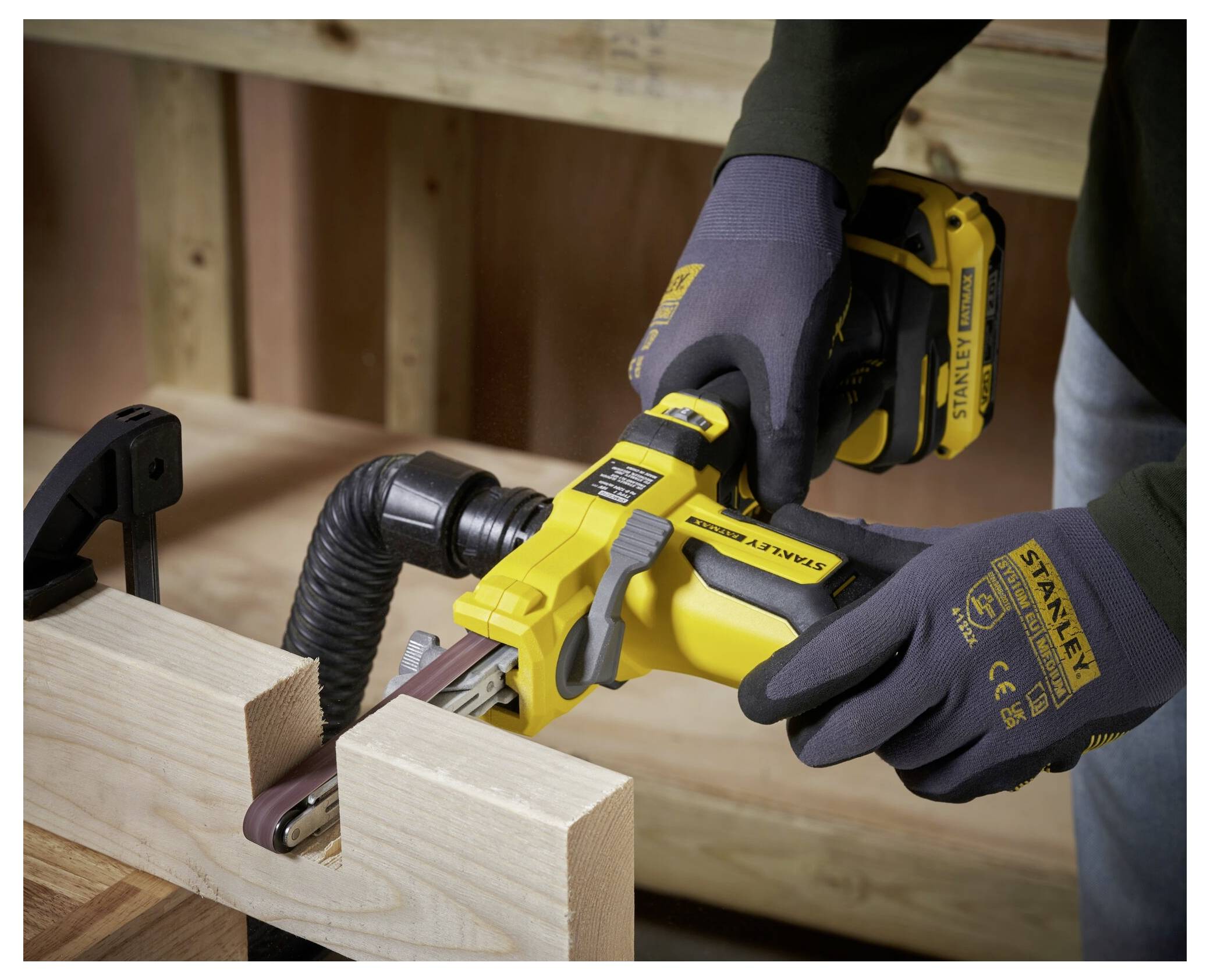 Eine Person in Handschuhen bedient einen gelben Schneeräumer auf einer schneebedeckten Oberfläche und stellt die Richtung des Auswurfschachts für die Schneeablagerung ein.