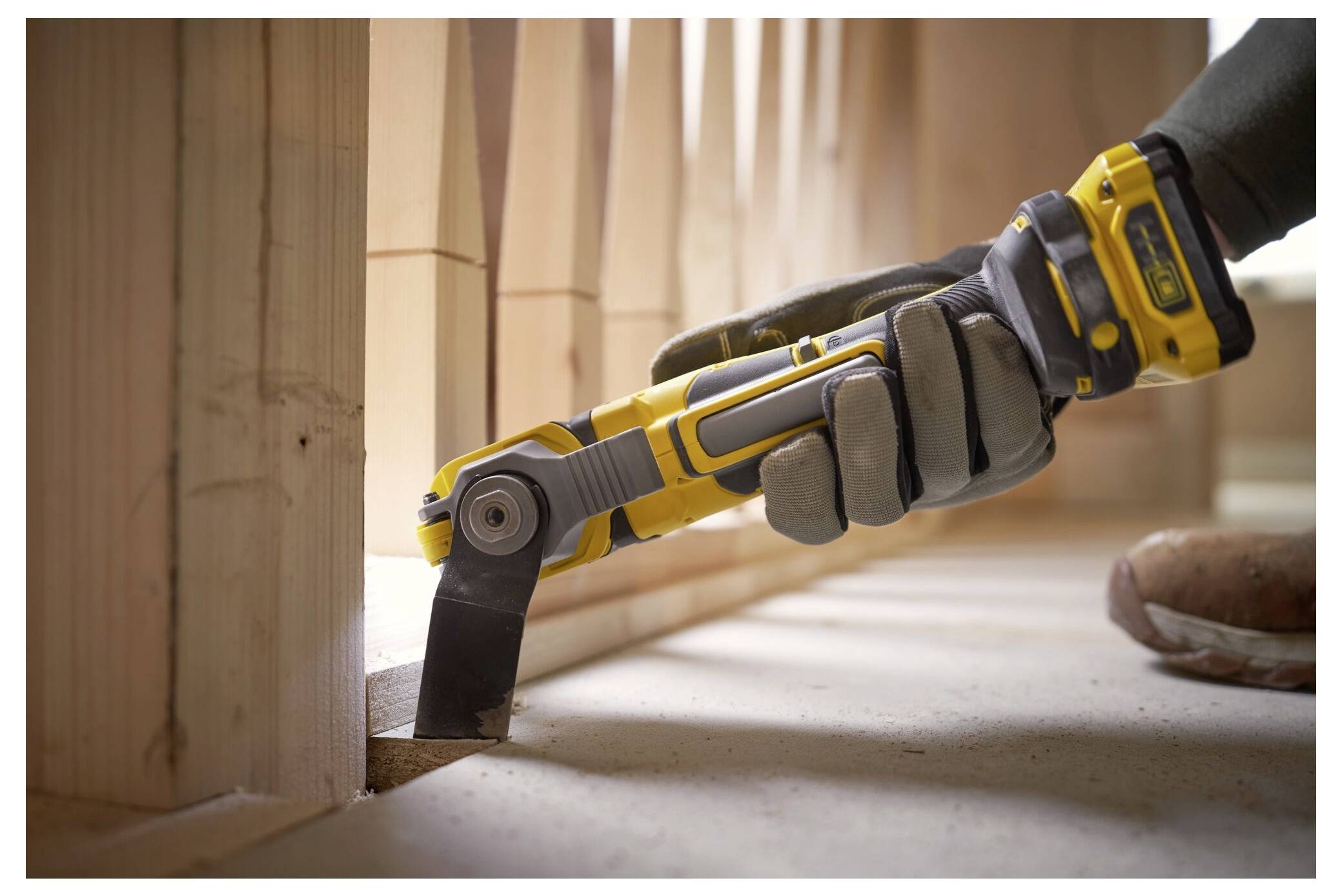 Eine behandschuhte Hand hält den Griff eines Elektroschraubers, auf dem 