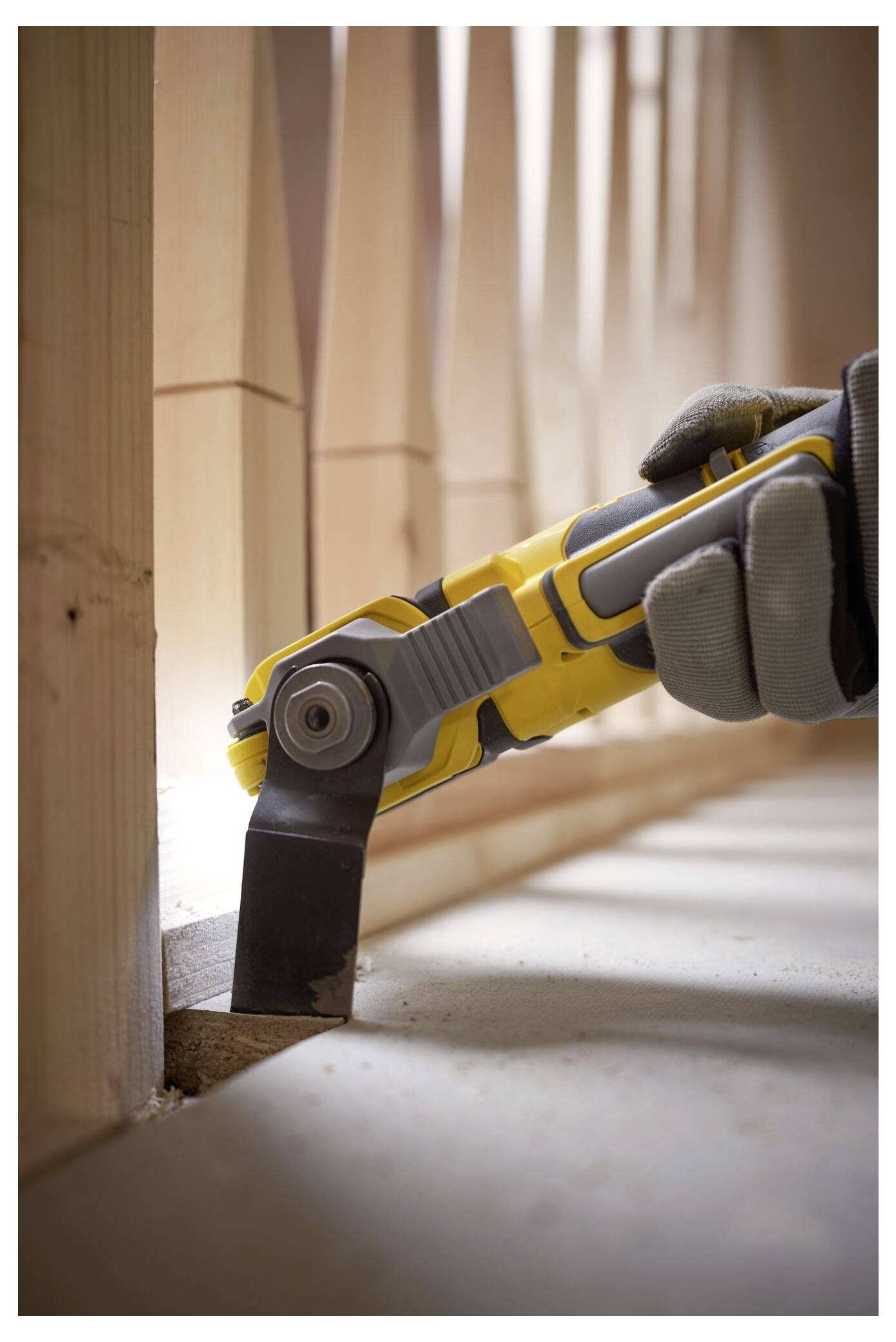 Eine behandschuhte Hand verwendet ein gelbes Schwingschleifw erkzeug, um eine Holzoberfläche zu schleifen, wobei der Fokus auf einer schmalen Nut zwischen Holzspindeln liegt.