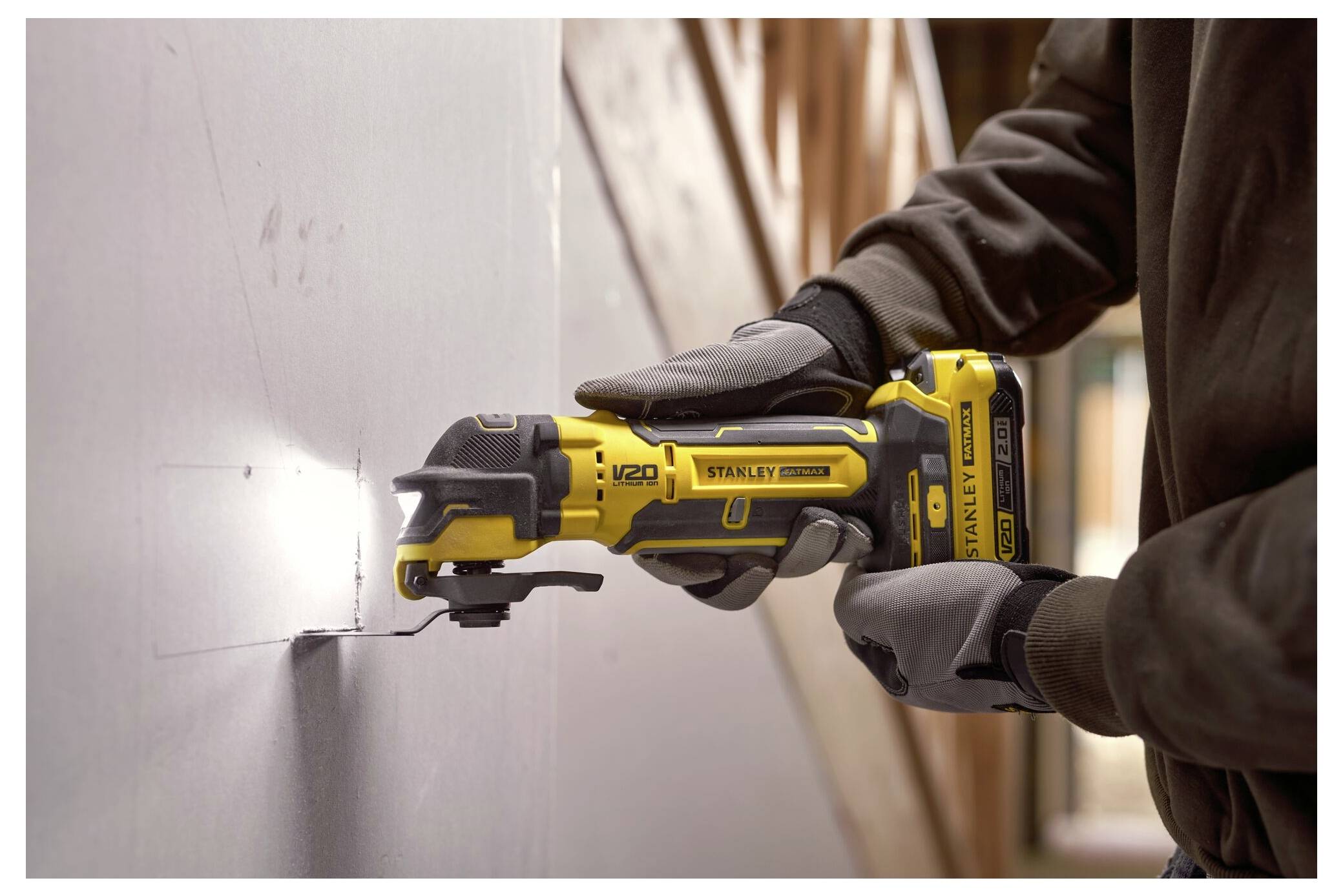 Ein Smartphone wird mit einem Kabel aufgeladen, das mit einem Stanley-Batterieladegerät verbunden ist. Eine Werkzeugkiste ist im Hintergrund auf einer Holzoberfläche sichtbar.