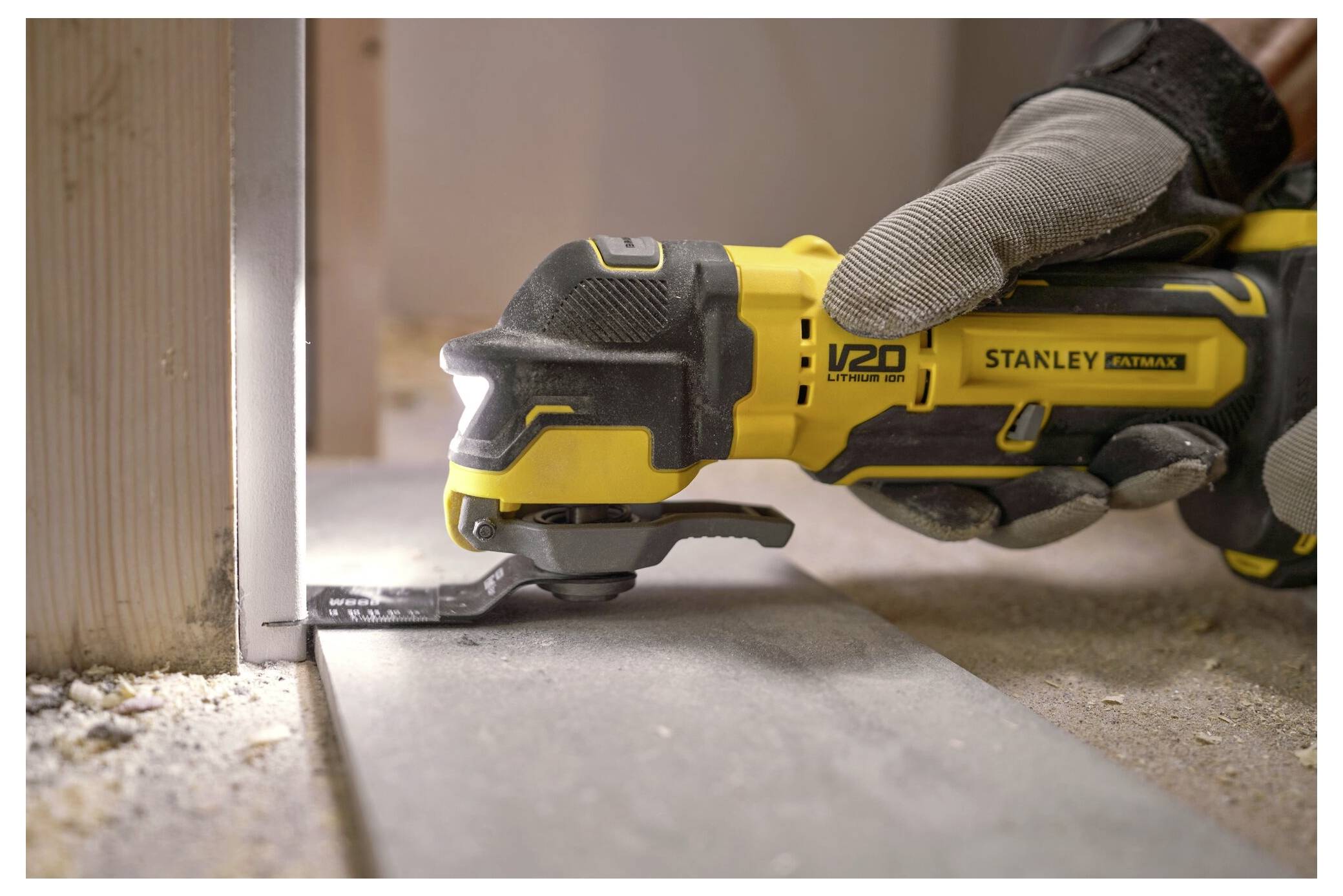 Eine Person in Handschuhen benutzt ein Stanley V20 Elektrowerkzeug, um ein Materialstück zuzuschneiden und demonstriert damit präzise Handwerkskunst in einer Baustelle.