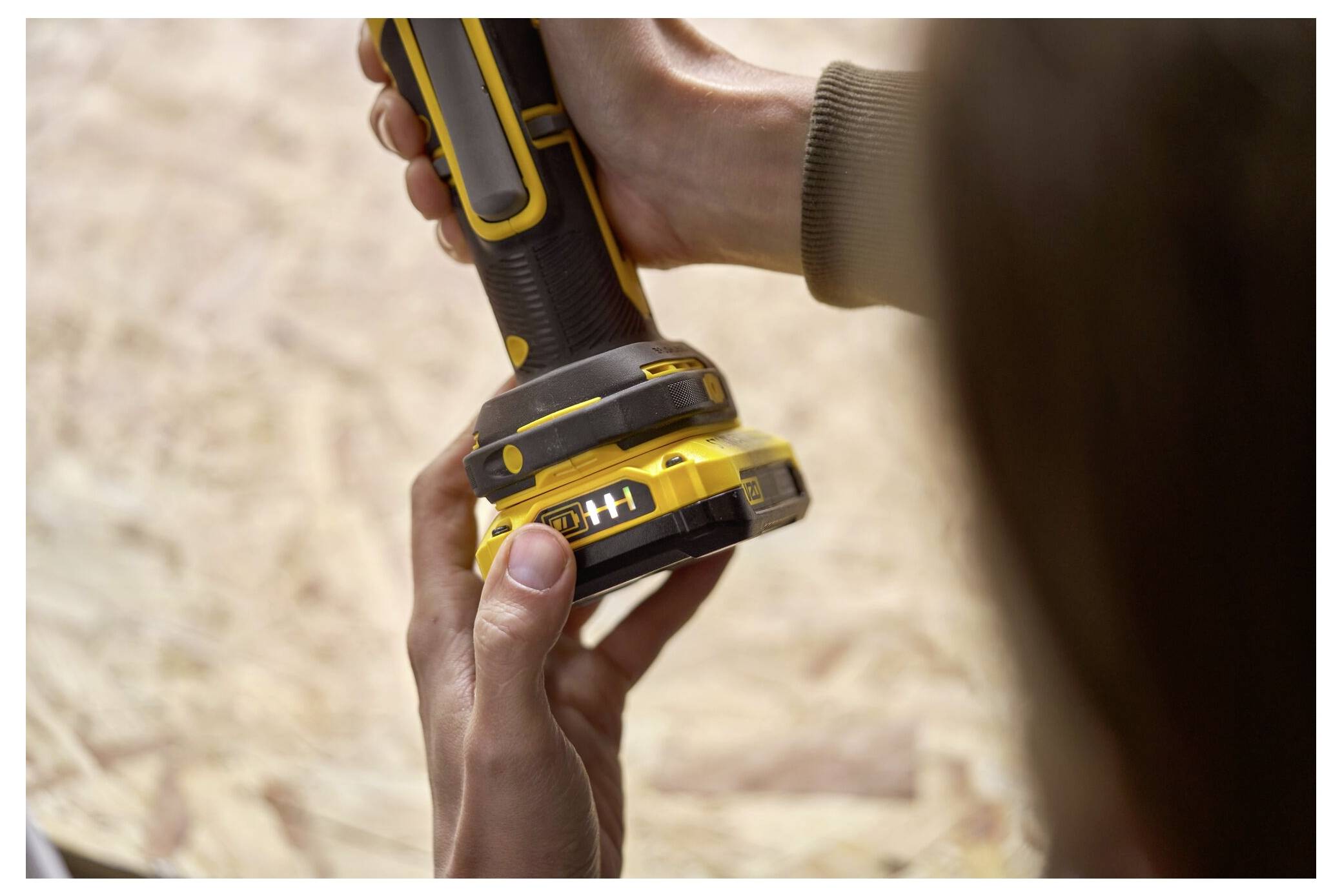 Eine Person, die ein gelb-schwarzes tragbares Elektrowerkzeug hält, wobei der Fokus auf dem Griff und der Kontrolle liegt.