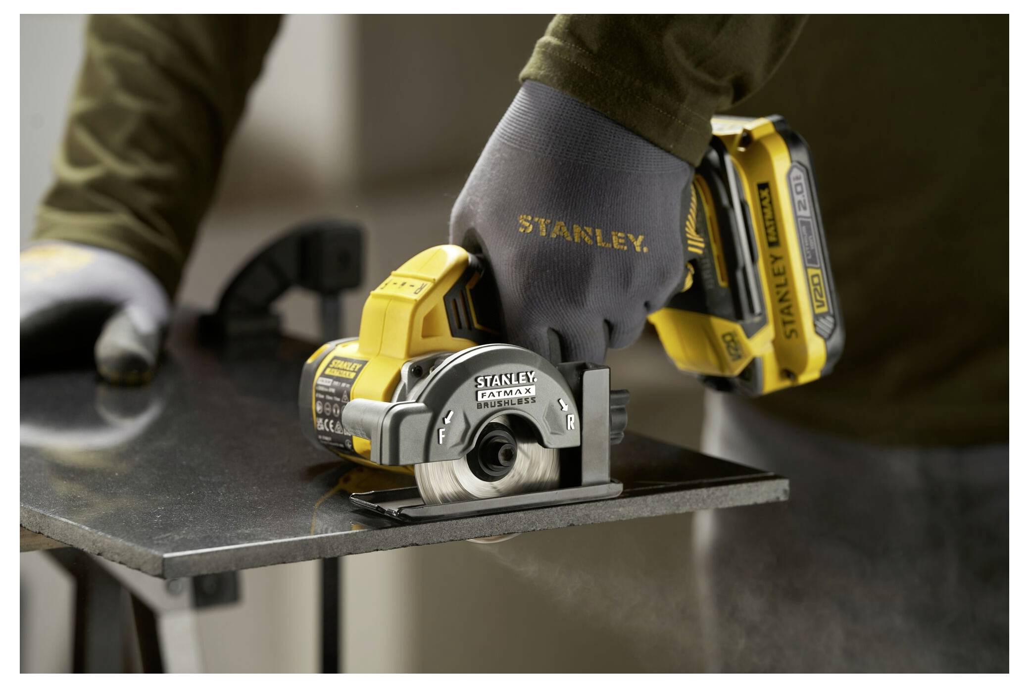 Eine Person verwendet eine Stanley Akku-Säge, um ein Metallstück zu schneiden, wobei sie zum Schutz Schutzhandschuhe und Schutzkleidung trägt.