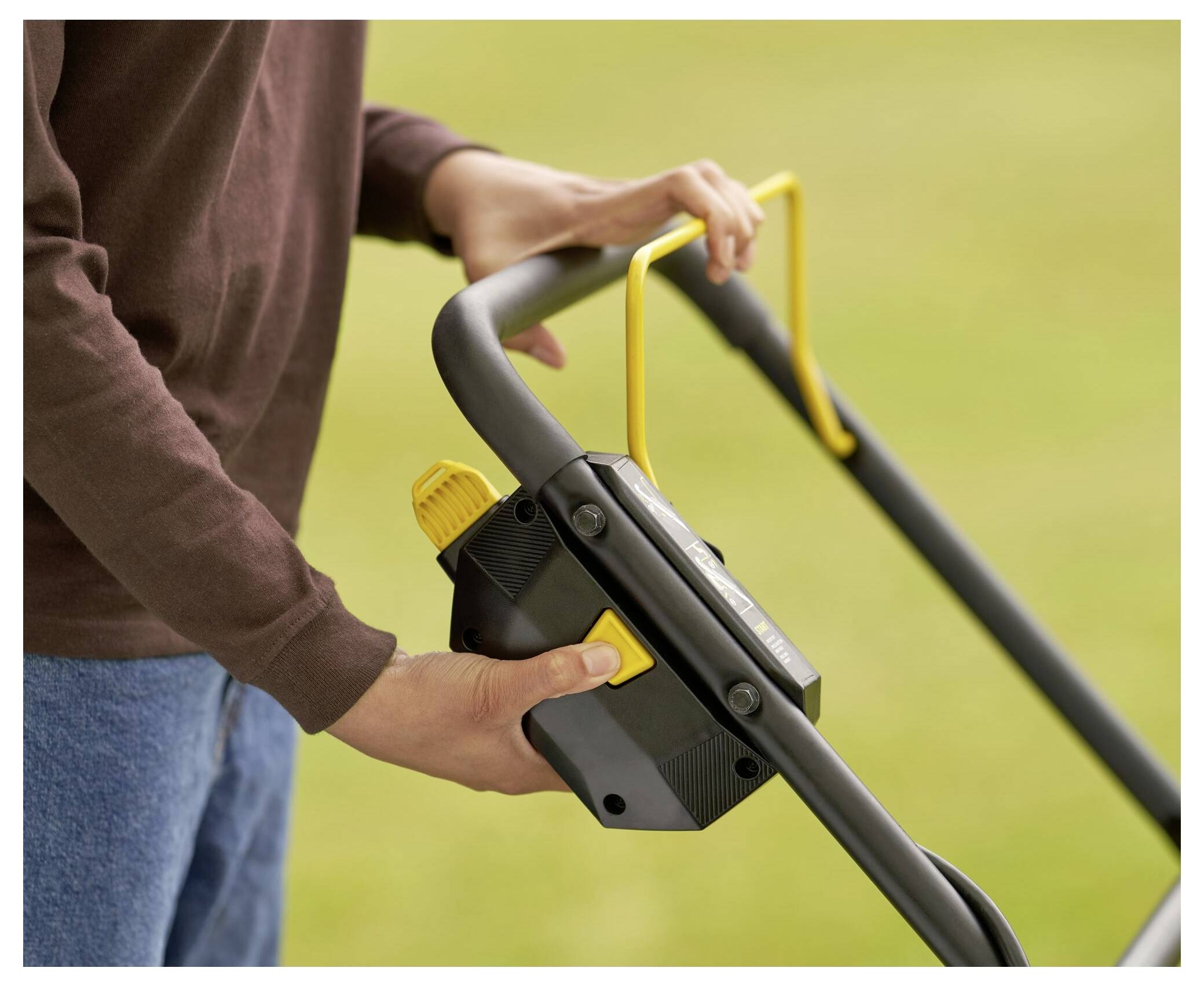 Eine Person bedient einen Rasenmäher und stellt den Steuerhebel am Griff ein.