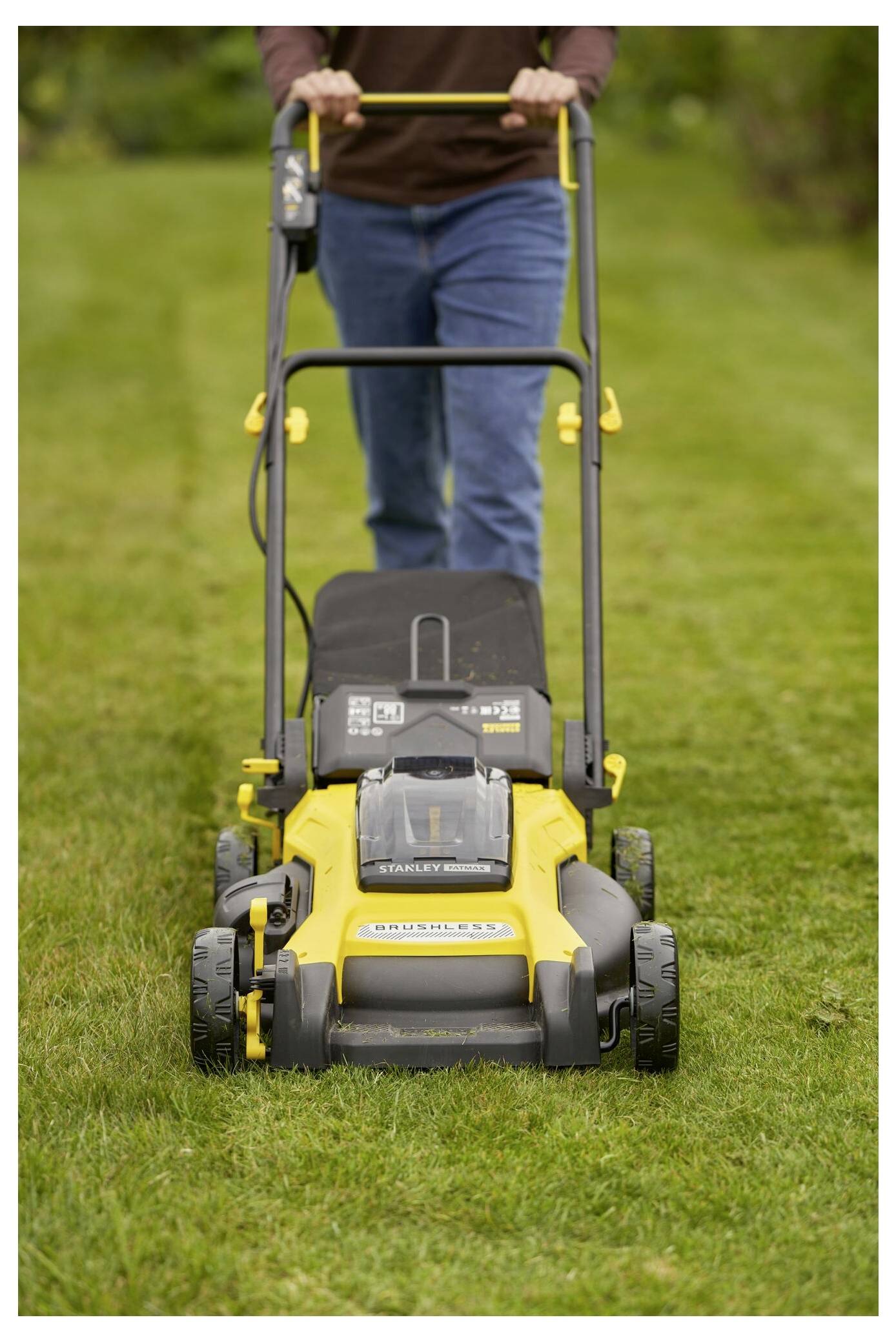 Eine Person mäht einen Rasen mit einem gelb-schwarzen Rasenmäher auf einer Grasfläche und konzentriert sich auf die Rasenpflege.
