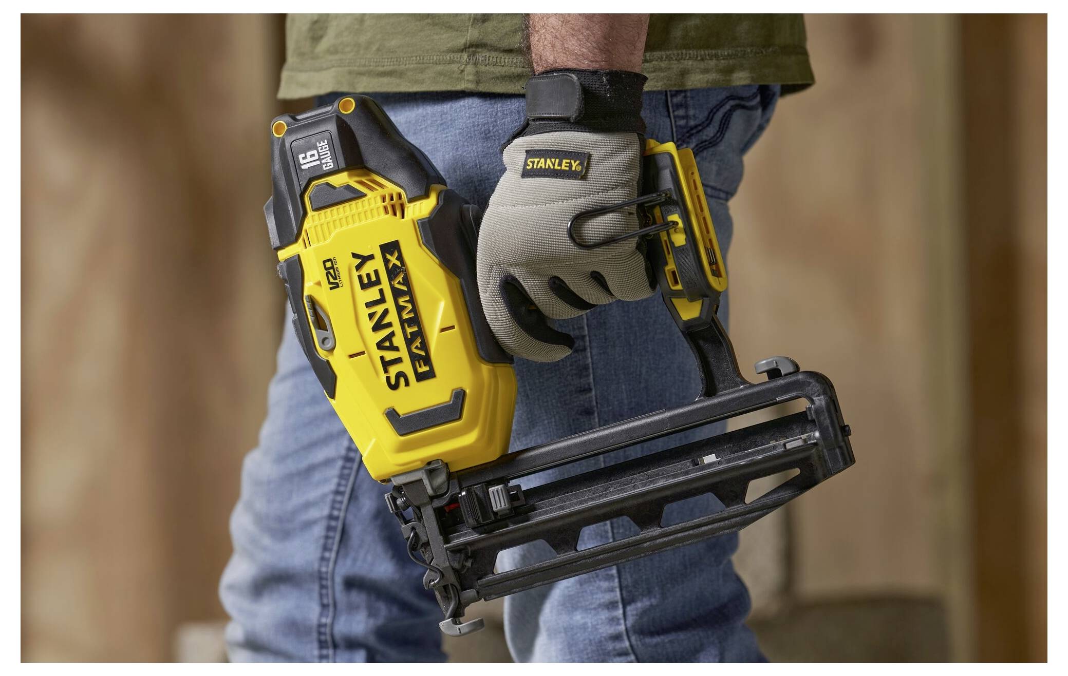 Eine Person in Handschuhen hält eine gelbe Nagelschussmaschine in einer Baustelle und hebt dabei das ergonomische Design und die Benutzerfreundlichkeit des Werkzeugs hervor.