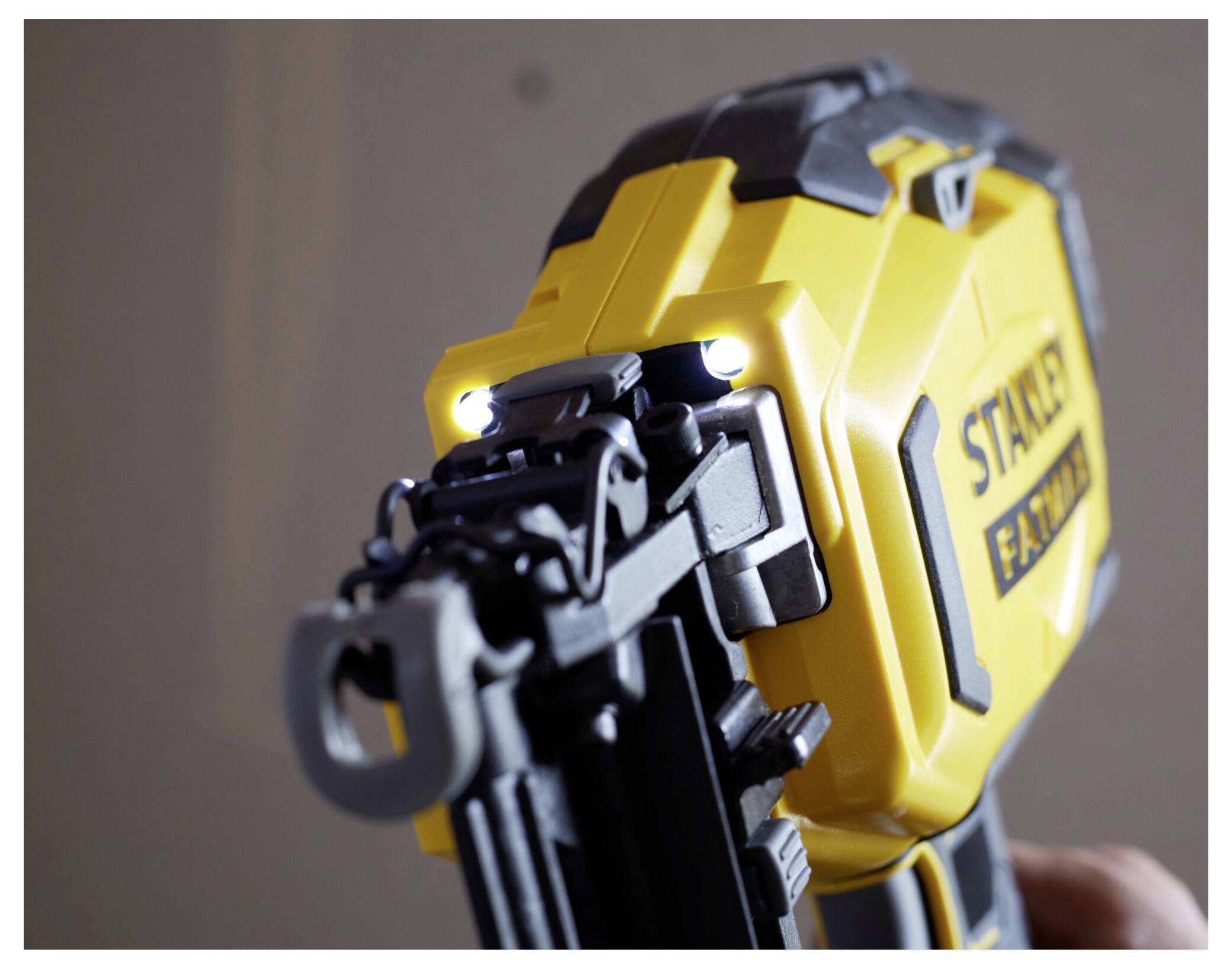 Nahaufnahme einer gelb-schwarzen Nagelschussmaschine mit LED-Leuchten, Markenname sichtbar, was darauf hinweist, dass sie einsatzbereit für den Einsatz im Bauwesen oder der Zimmerei ist.