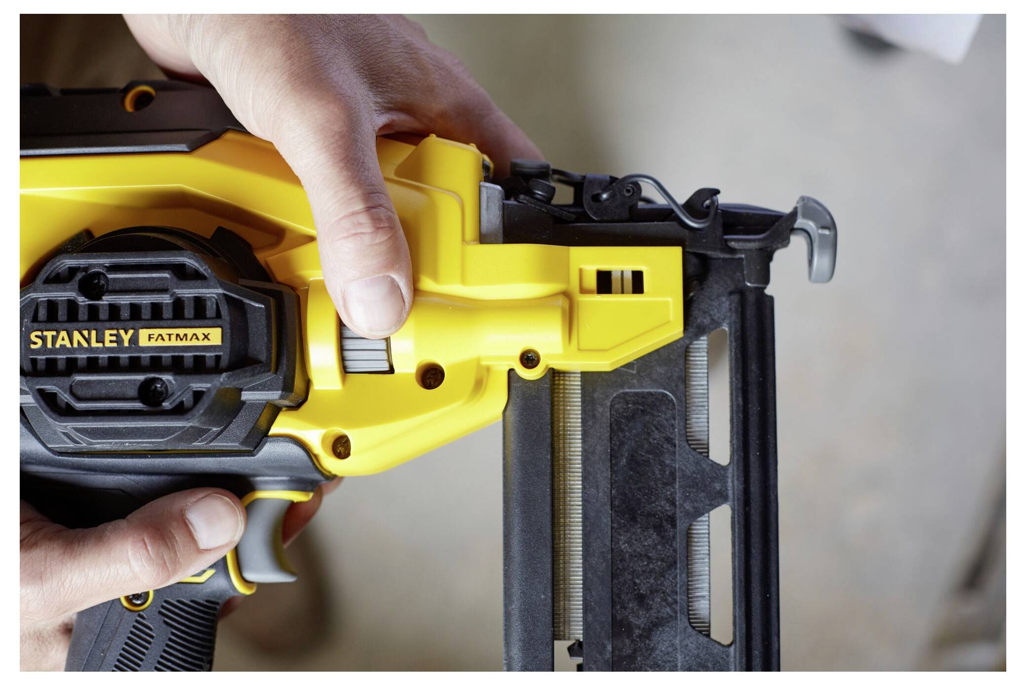 Eine Person benutzt eine gelbe Stanley Fatmax Nagelschussmaschine und hält sie mit beiden Händen.