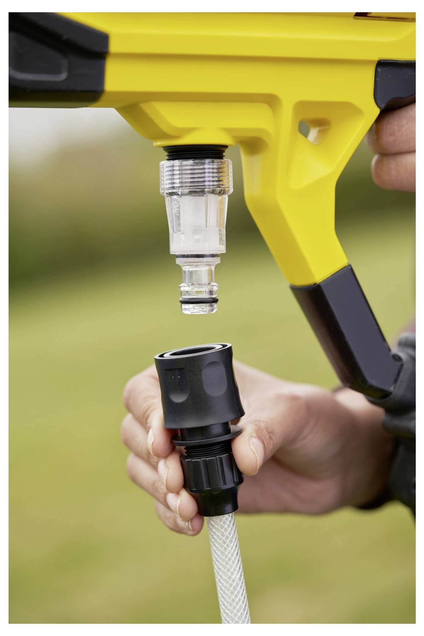 Eine Hand verbindet eine schwarze Gartenschlauch-Anschlussfitting mit einer gelben Düsenaufsatz-Verbindung, die die Einrichtung von Bewässerungs- oder Gartengeräten darstellt.