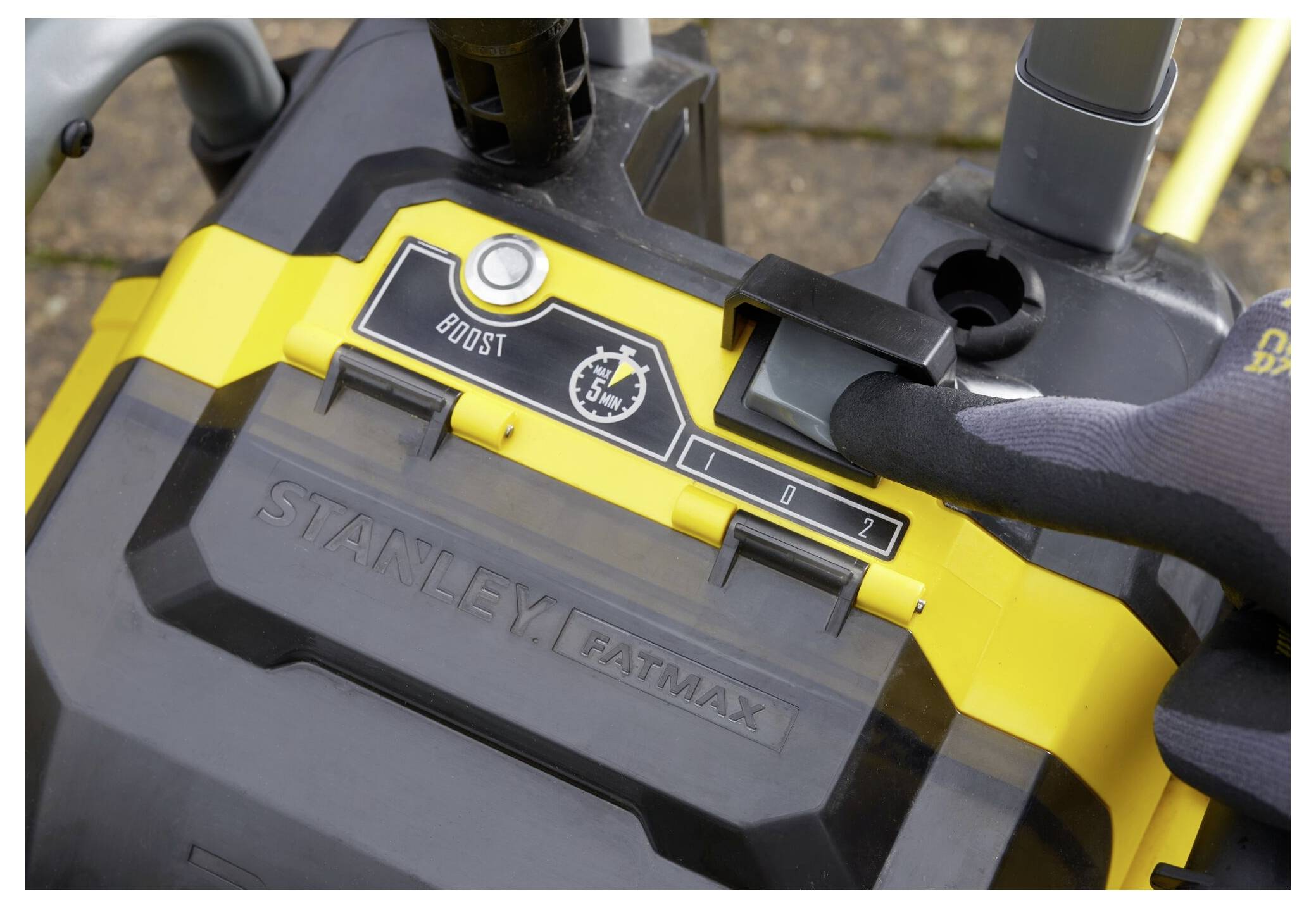 'Eine Nahaufnahme eines Stanley FatMax Batterieladegeräts mit einer behandschuhten Hand, die die Einstellungen auf dem digitalen Anzeigefeld anpasst und den 