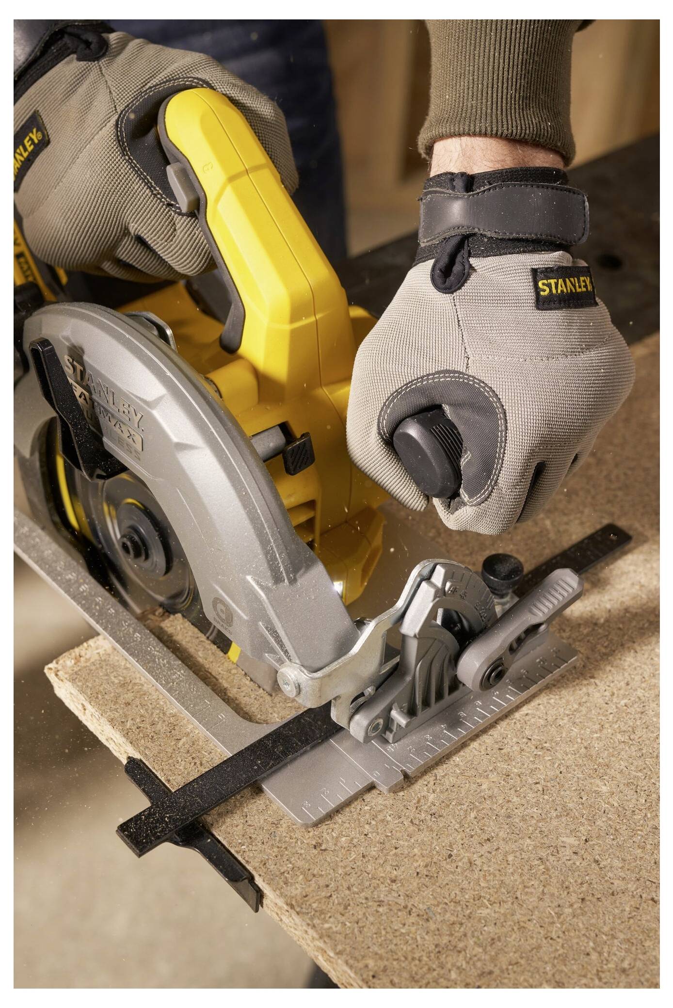 Eine Person benutzt eine gelbe Kreissäge, um ein Holzstück zu schneiden. Die Person trägt graue Handschuhe zur Sicherheit.