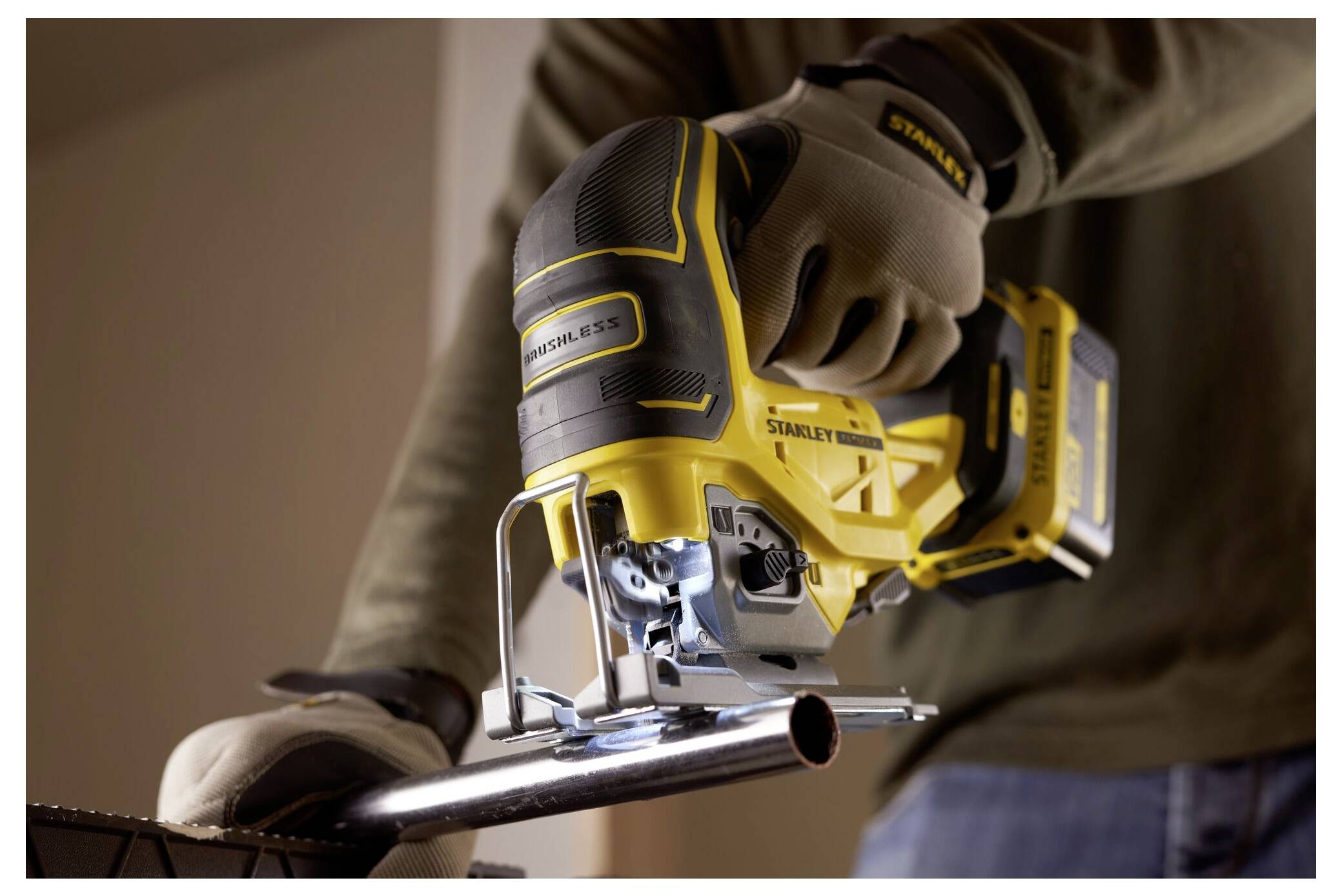 Eine Person mit Handschuhen benutzt eine gelbe Elektrostichsäge, um ein Metallrohr zu schneiden, wobei der Fokus auf Präzision und Sicherheit liegt.