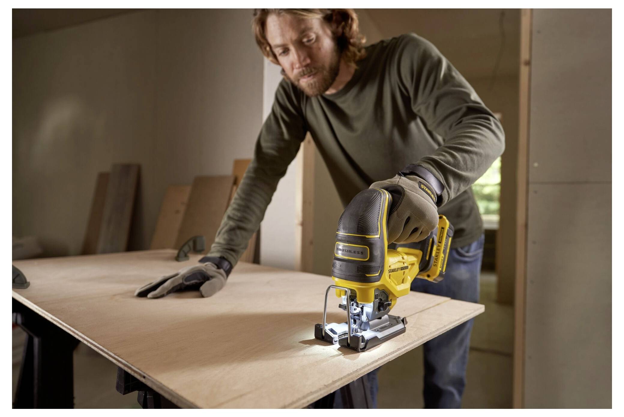 Eine Person benutzt eine Stichsäge, um ein Sperrholzstück in einer Werkstattsituation zu zuschneiden. Der Fokus liegt auf der Holzbearbeitungsaufgabe.