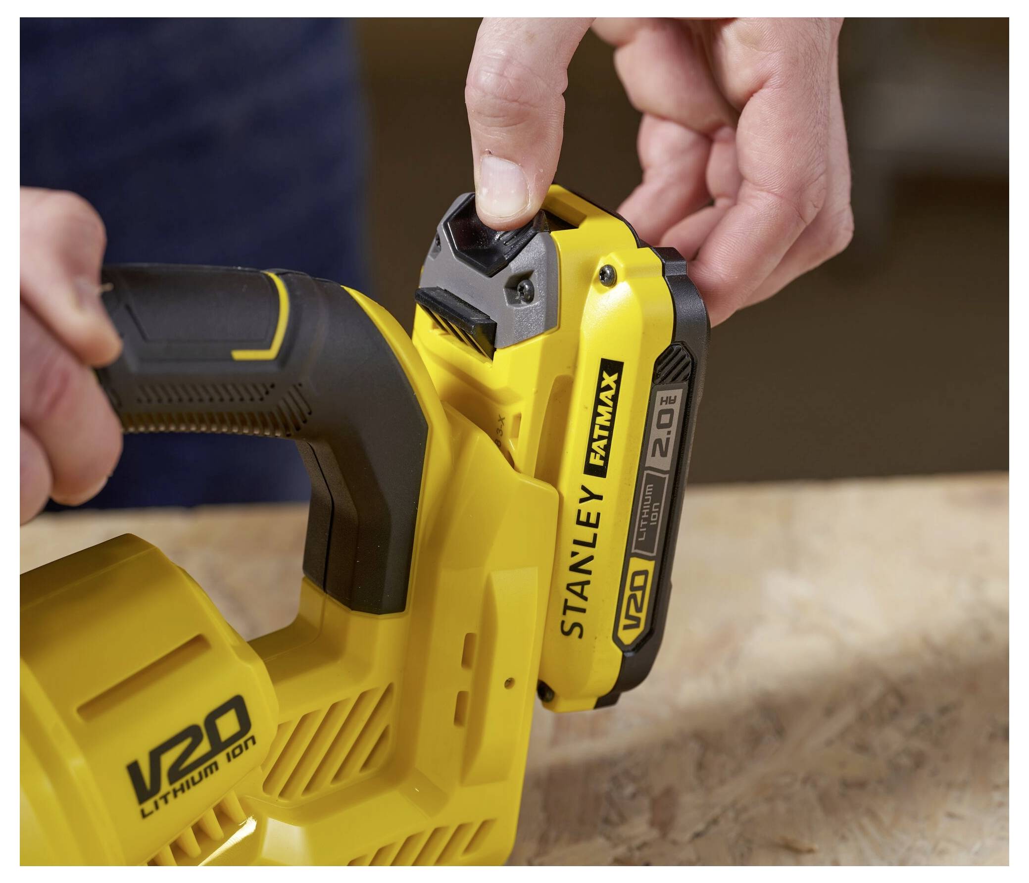 Eine Person befestigt eine Lithium-Ionen-Batterie an einem Stanley Fatmax kabellosen Elektrowerkzeug und zeigt den Verriegelungsmechanismus des Geräts.