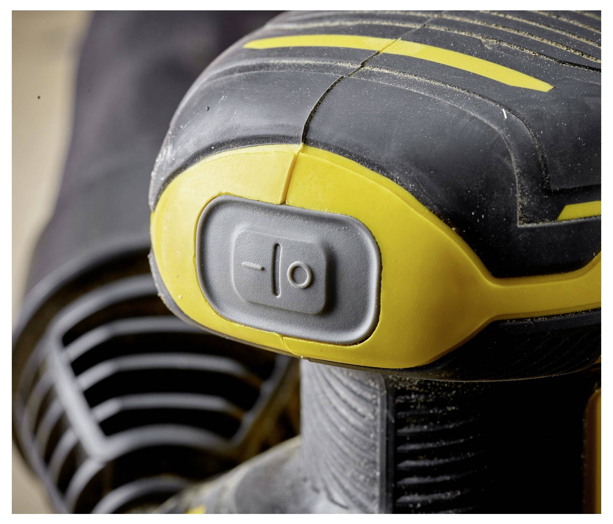 Eine Nahaufnahme des Griffs und des Schalters eines Elektrowerkzeugs, die eine strukturierte Griffoberfläche und einen grauen Netzschalter zeigen, vor einem unscharfen Hintergrund.