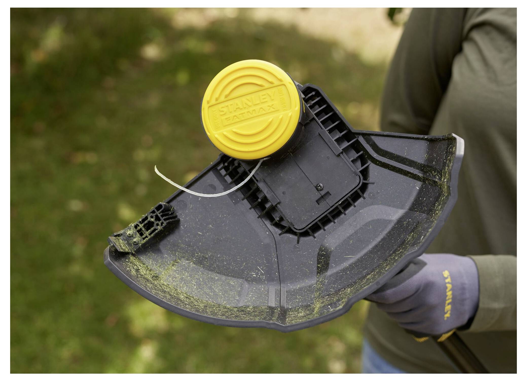 Eine Person hält einen Rasentrimmer mit einer gelben 