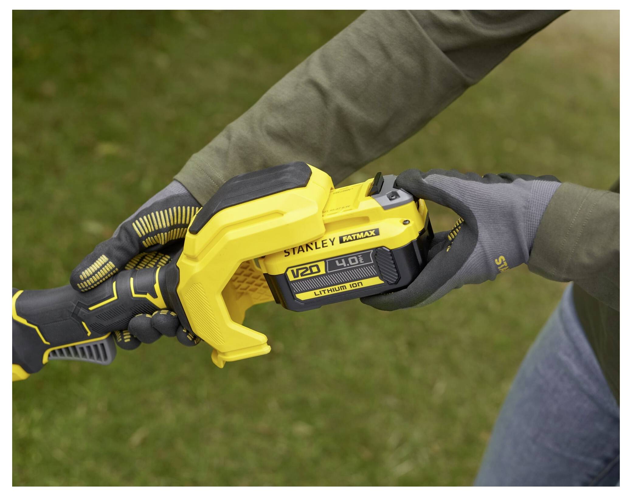 Nahaufnahme einer Person, die ein gelb-schwarzes Elektrowerkzeug mit wiederaufladbarem Akku im Freien verwendet und Handschuhe trägt, um zusätzliche Sicherheit zu gewährleisten.