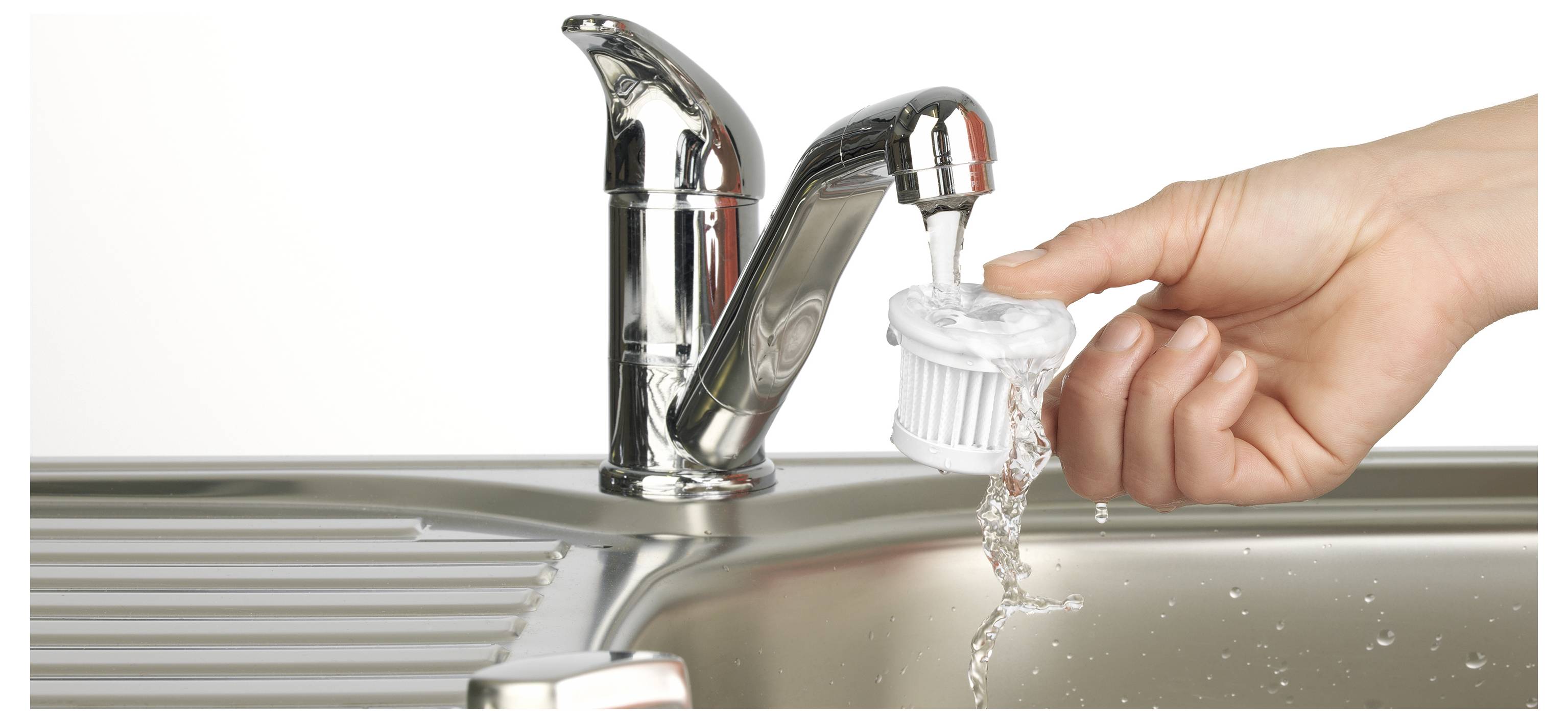Eine Hand hält einen kleinen Filter unter einen Wasserstrom aus einem glänzenden Wasserhahn in der Küche, um zu zeigen, wie man den Filter ausspült und reinigt.