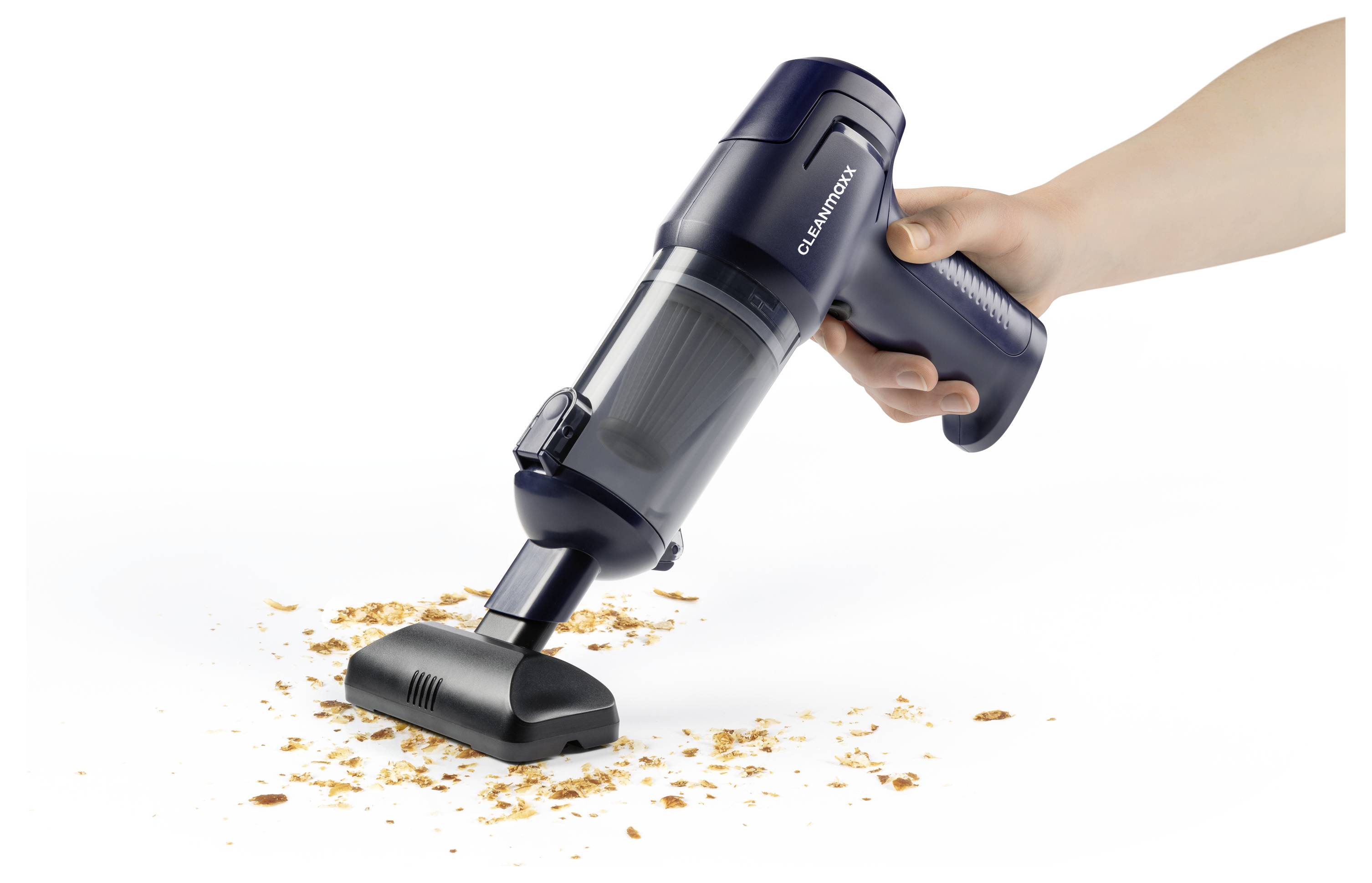 Eine Hand benutzt einen kompakten schnurlosen Staubsauger, um Krümel von einer weißen Oberfläche aufzusaugen.