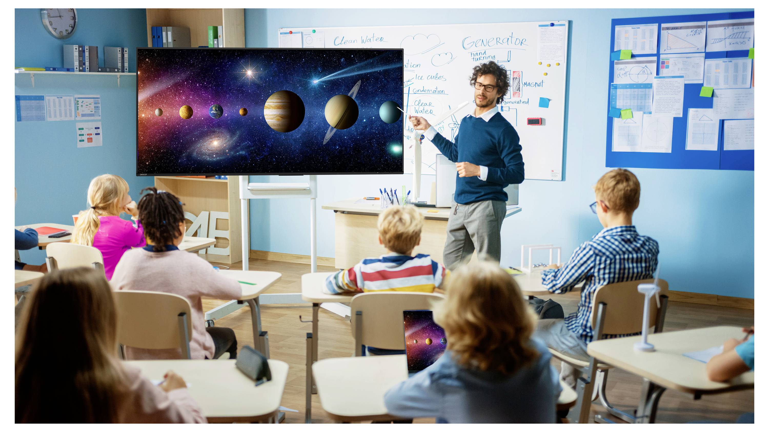Der Lehrer präsentiert ein Diagramm des Sonnensystems auf einem Klassenzimmerbildschirm, während Schüler an ihren Schreibtischen sitzen und zuschauen.