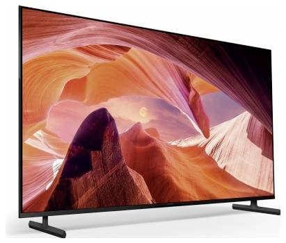 Flach-Fernseher zeigt eine lebendige Canyonlandschaft mit rot-orangefarbigen Felsformationen und einem rosa Himmel auf einem Ständer vor weißem Hintergrund.