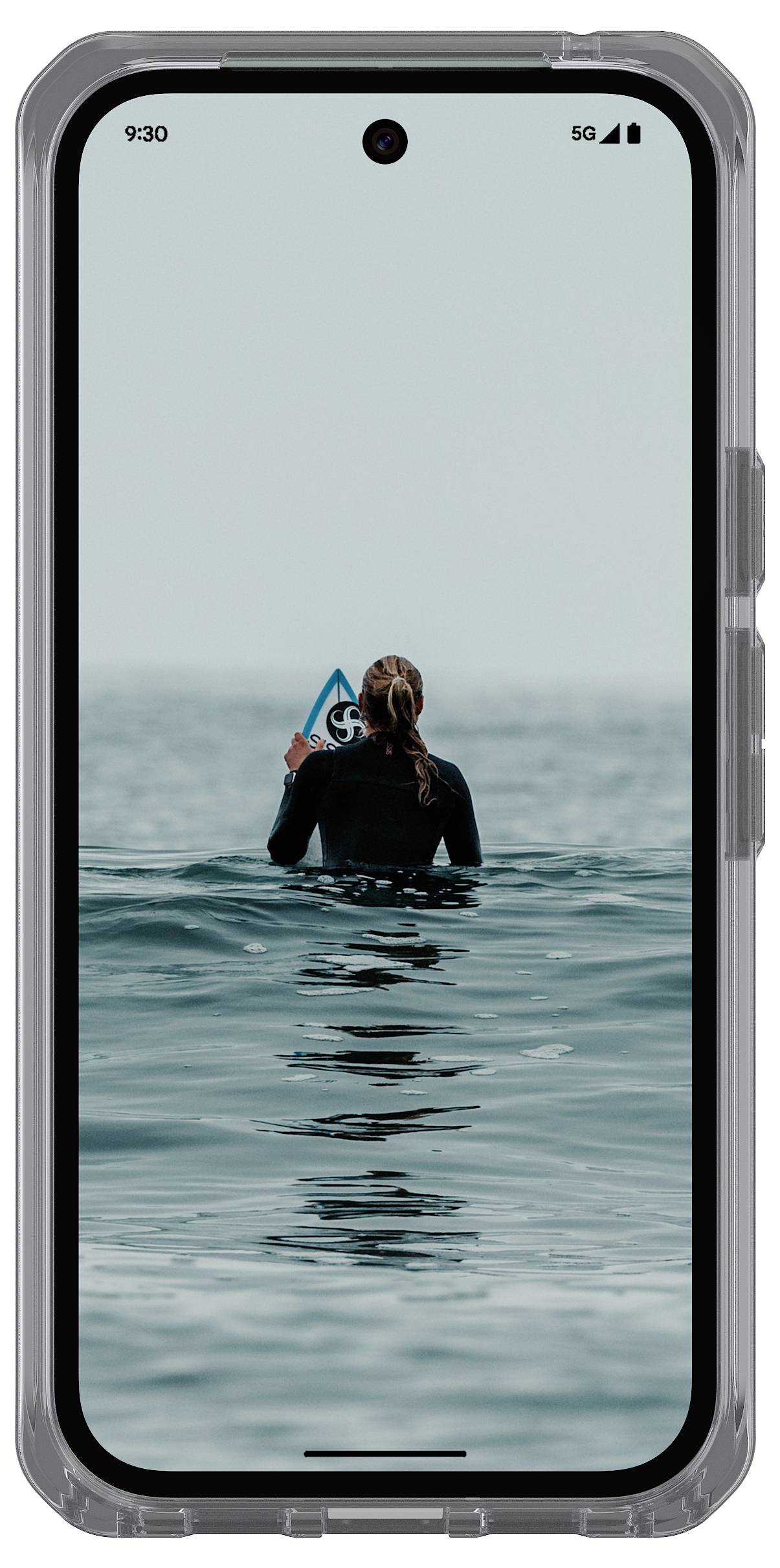 Ein Smartphone-Bildschirm zeigt eine Person in einem Neoprenanzug, die im Meer steht, ein blaues Surfbrett hält und von hinten betrachtet wird.