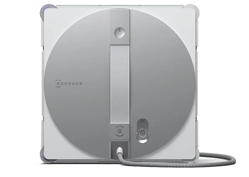 Ein quadratisches robotergestütztes Reinigungsgerät von ECOVACS mit einem grauen kreisförmigen Design auf der Vorderseite und einem angeschlossenen Stromkabel am unteren Ende.